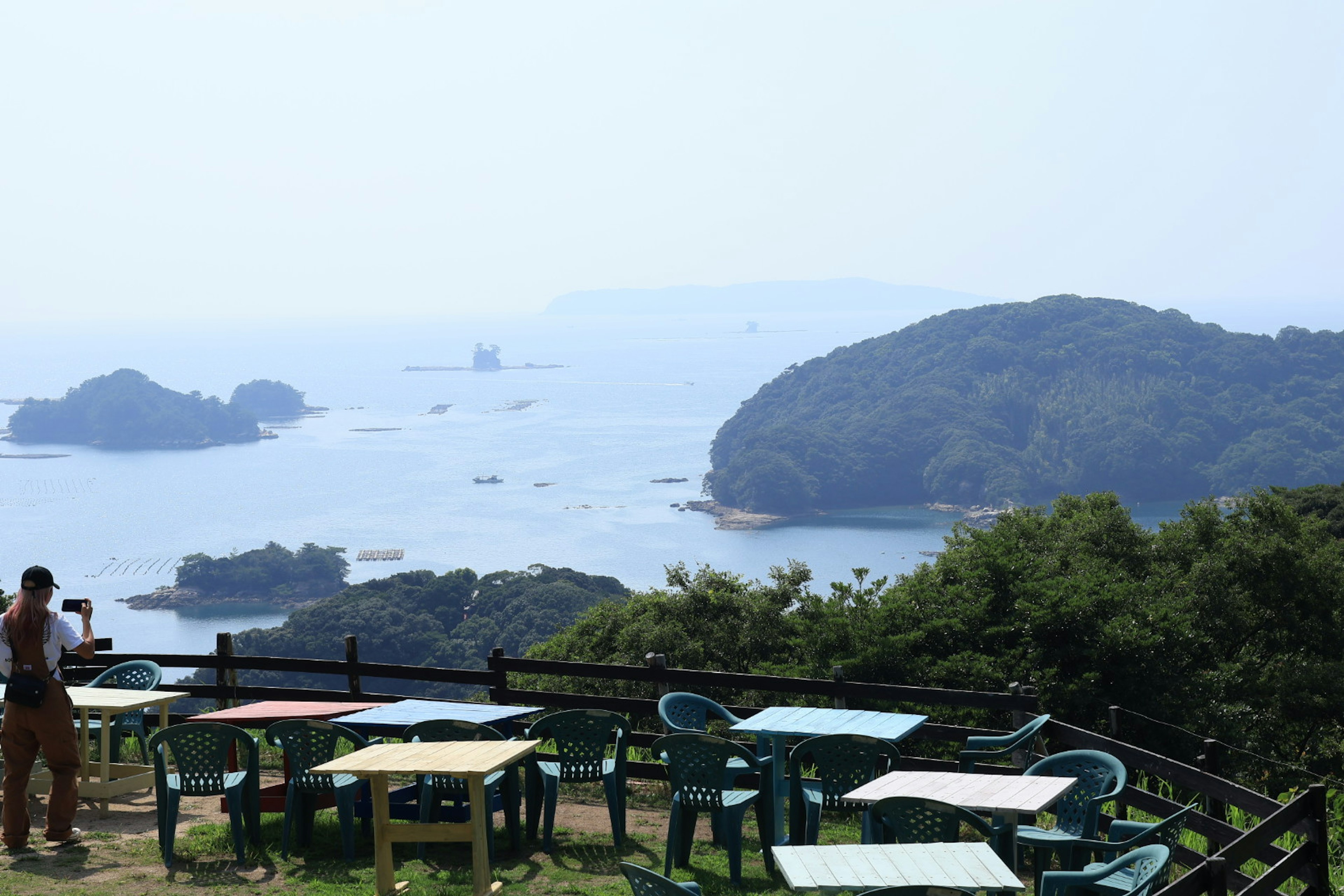 海の景色を望むカフェテラス 緑の木々と青い椅子