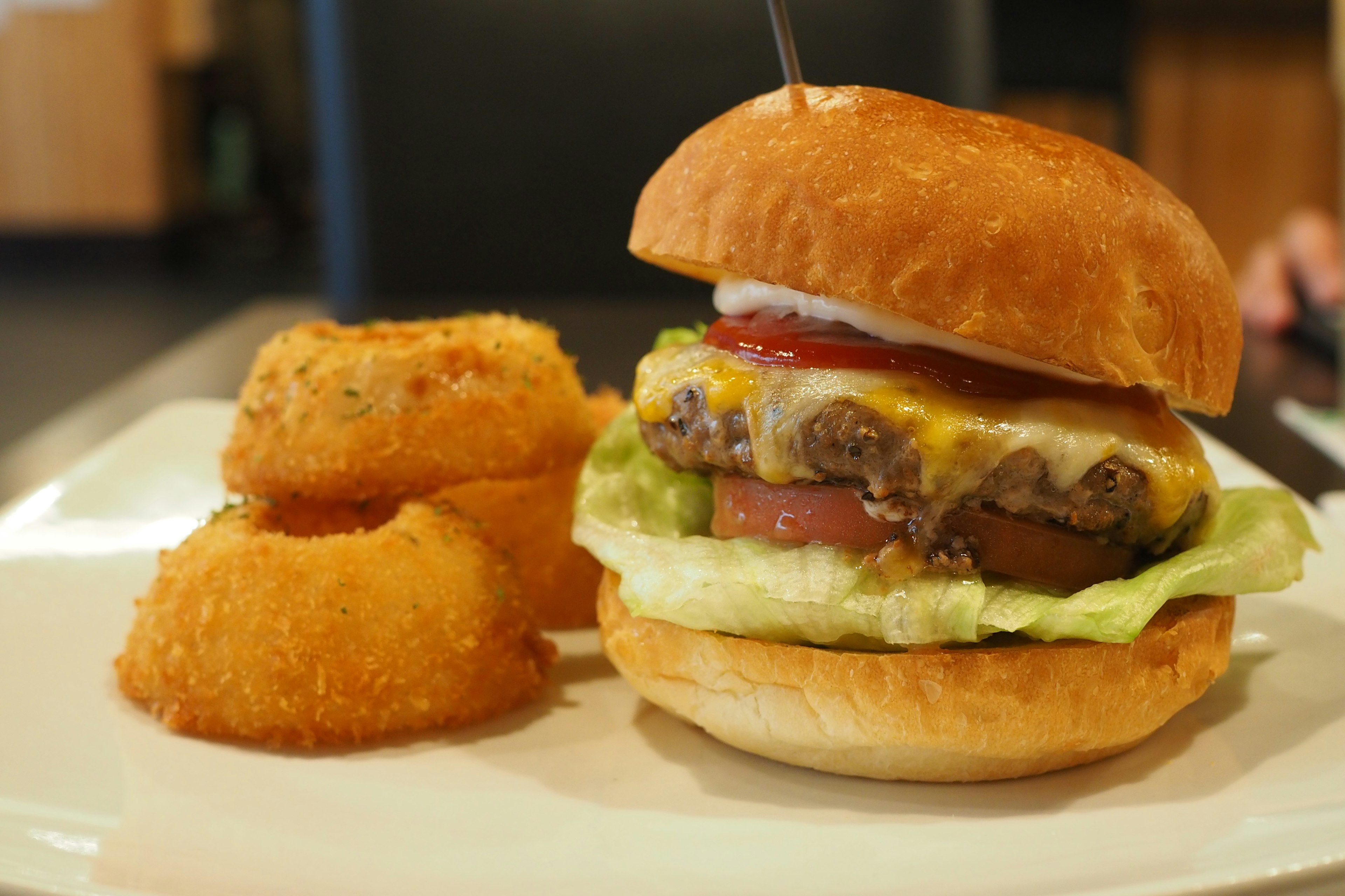 Hamburger juicy dengan onion rings renyah disajikan di piring