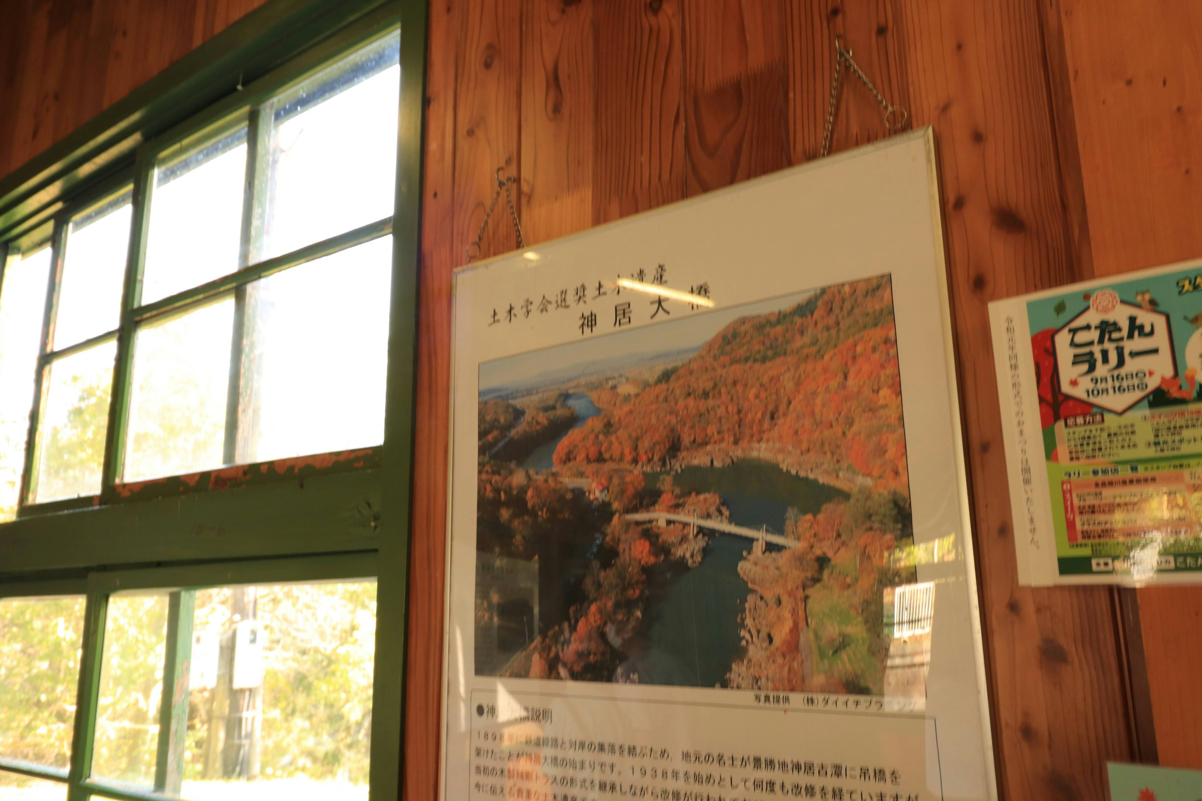 Affiche d'un paysage accrochée sur un mur en bois avec des fenêtres vertes