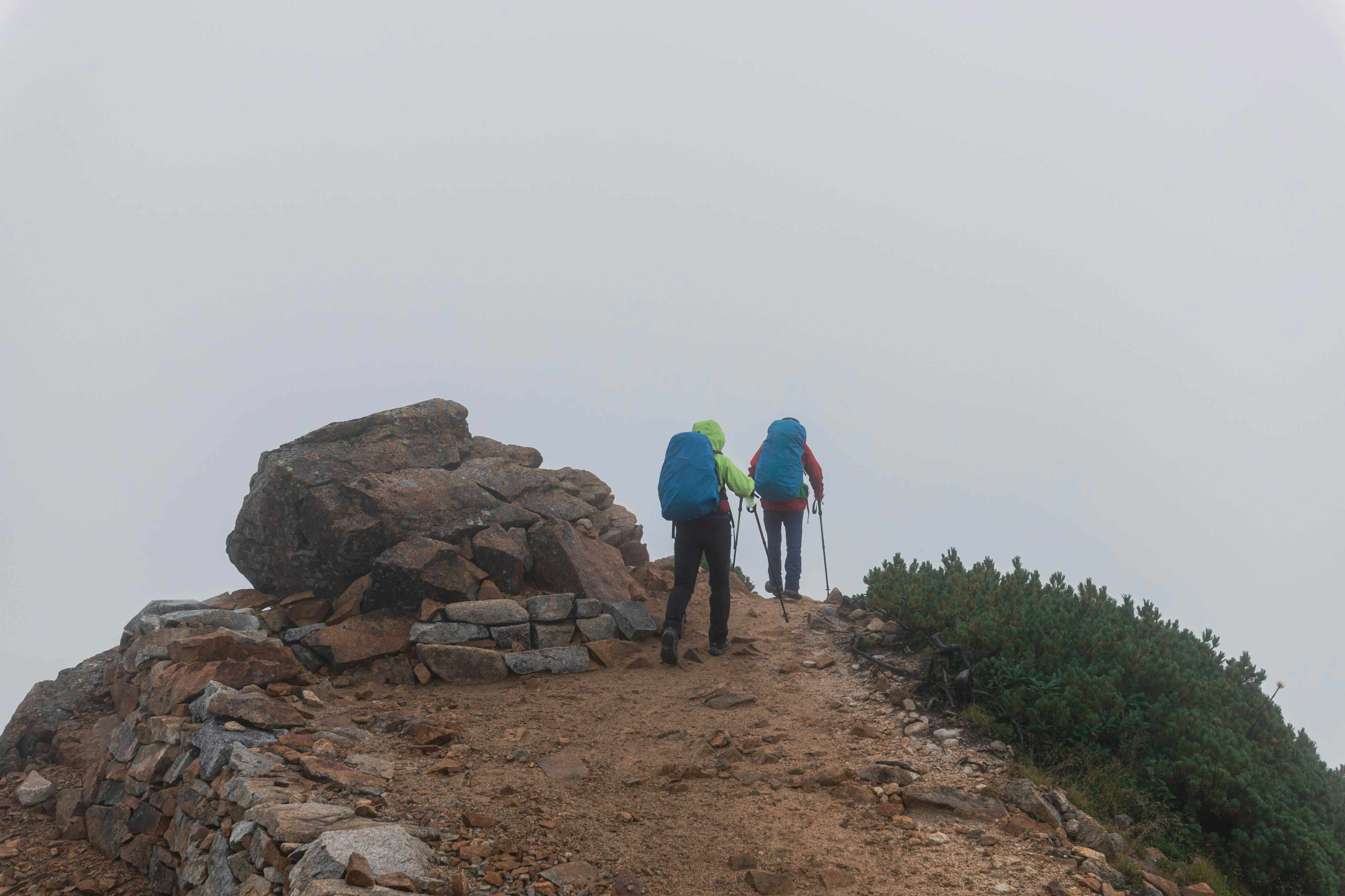 Dos excursionistas caminando por un sendero rocoso en la niebla