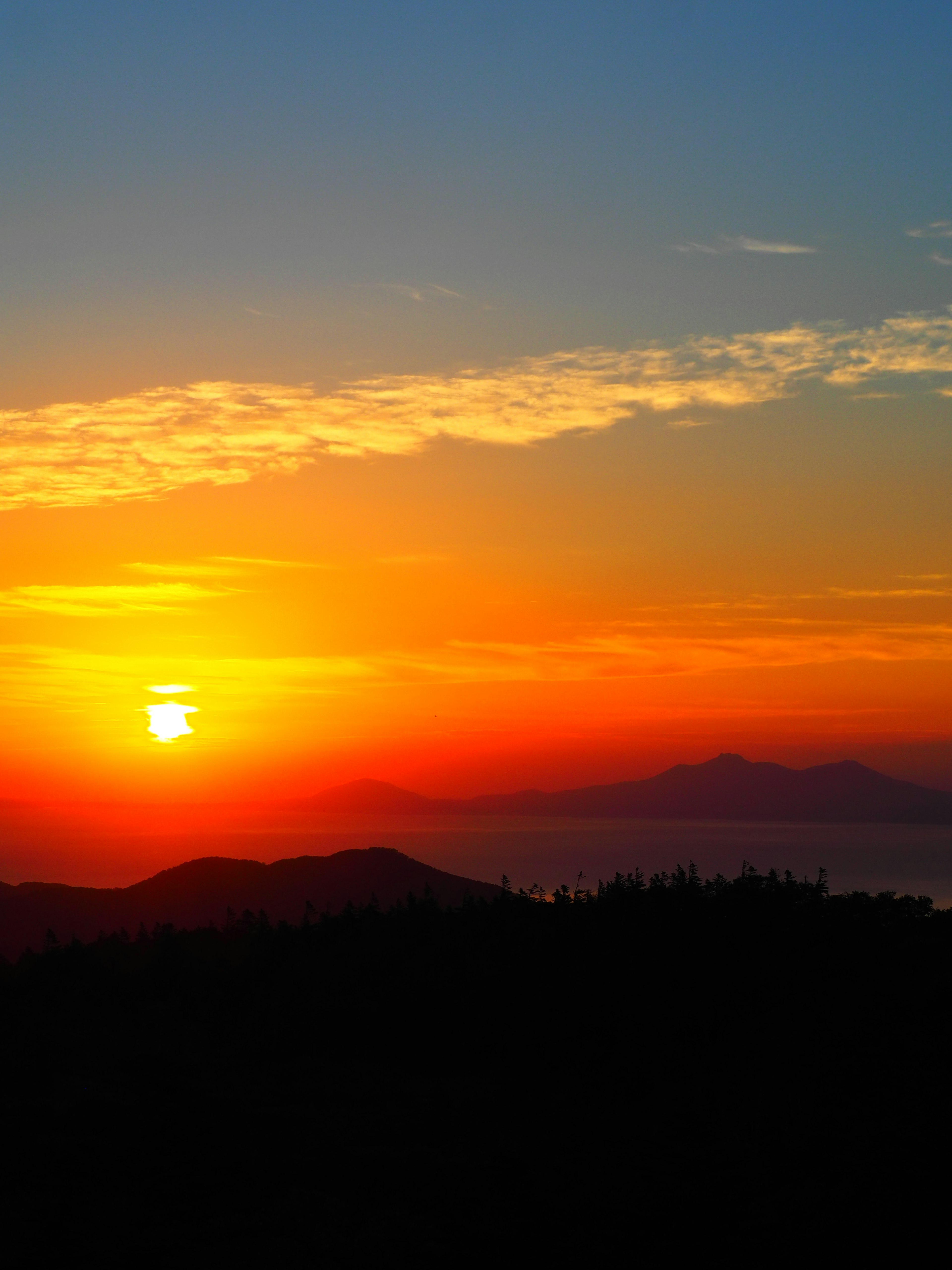 Hermoso paisaje de atardecer con un cielo naranja y azul vibrante montañas al fondo