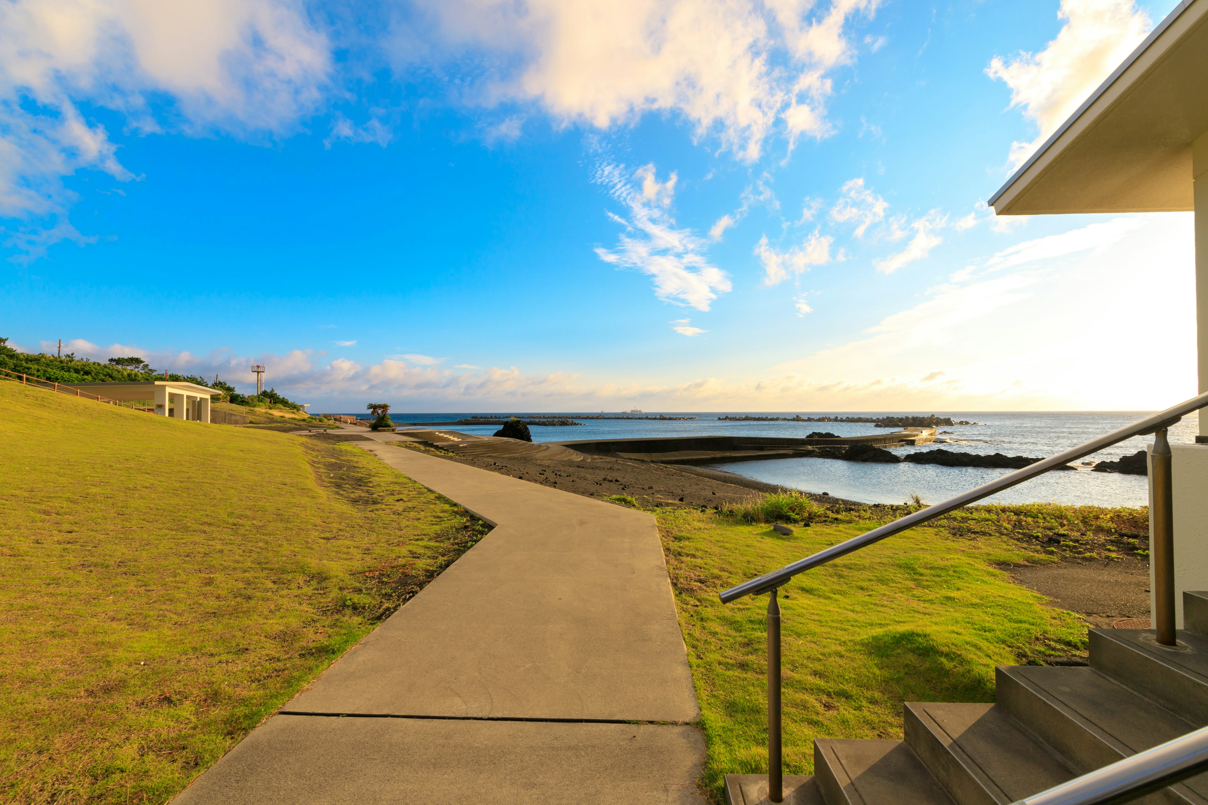 Coastal scene with blue sky and clouds green grass and a pathway