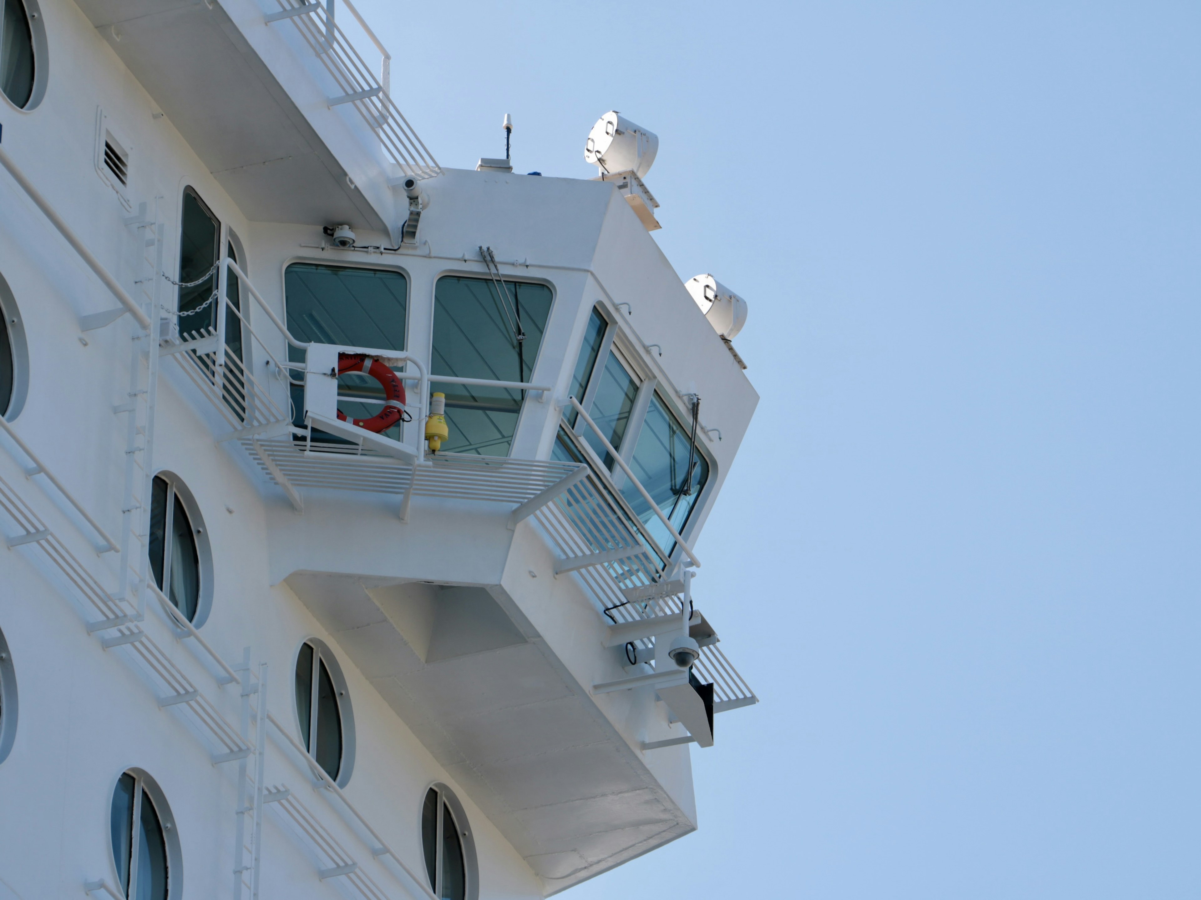 Close-up of a ship's bridge white ship's side blue sky background