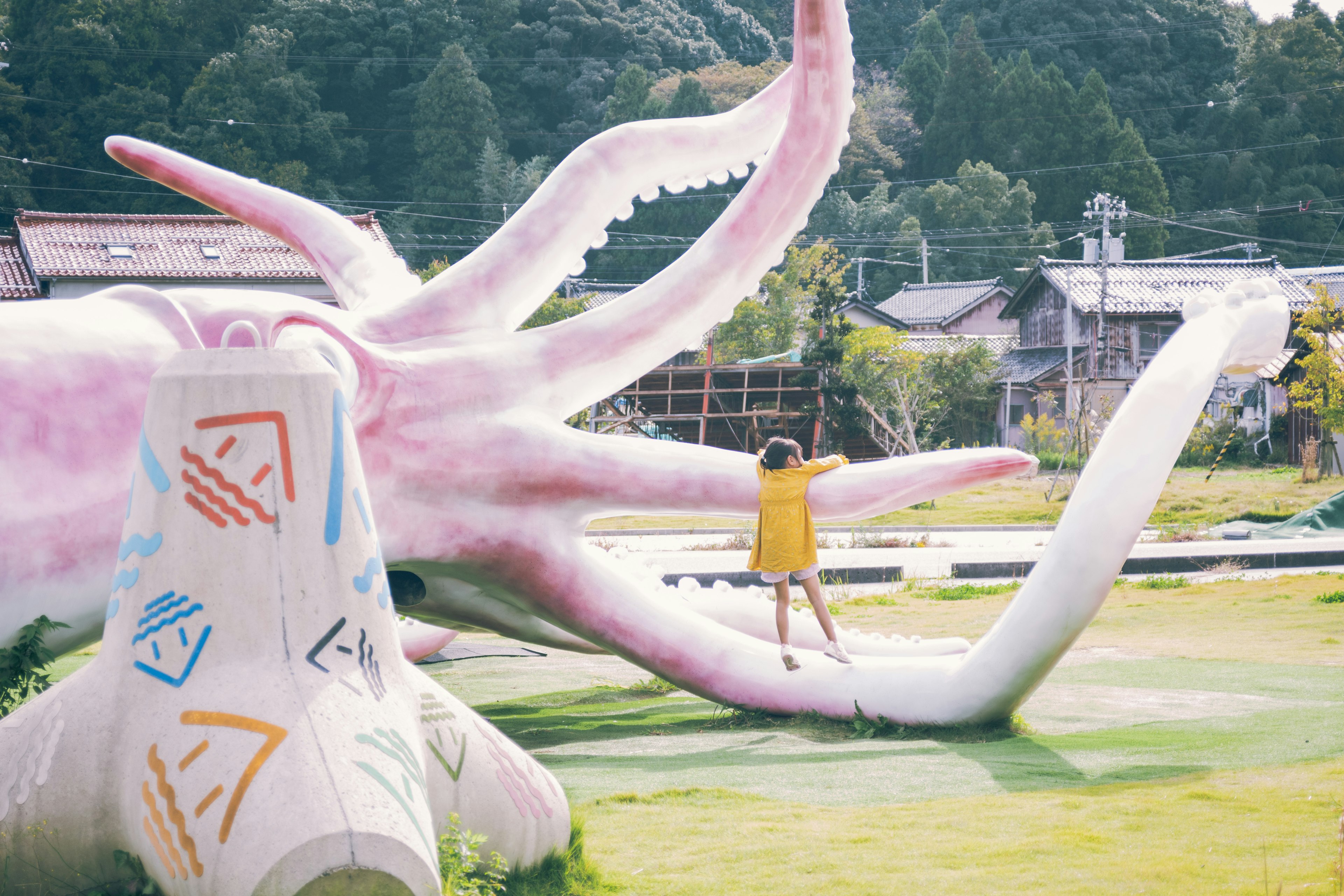 Bambino che gioca su una scultura di polpo rosa gigante