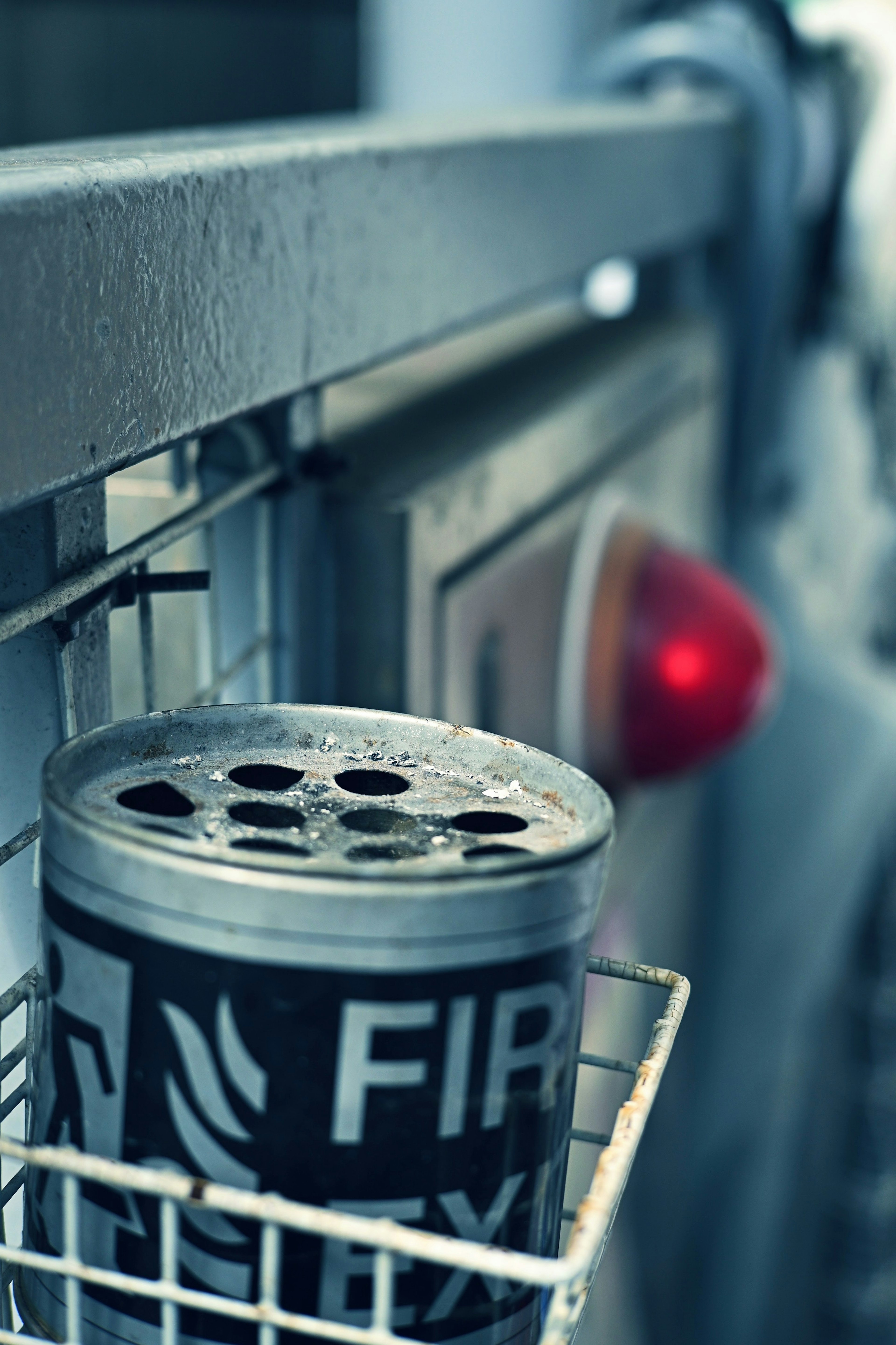 Image of a fire extinguisher can placed in a basket with a red light in the background