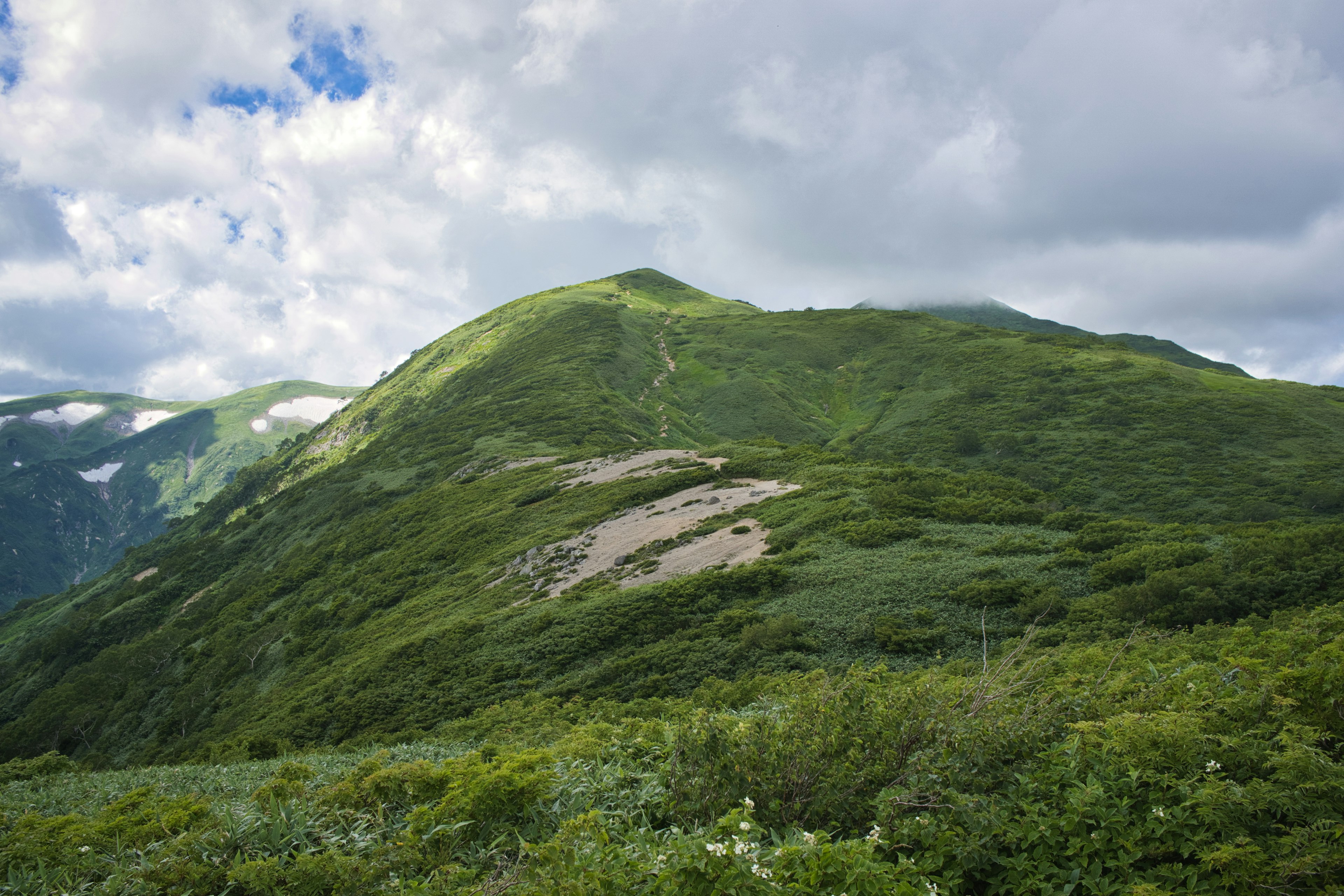 翠綠的山丘在多雲的天空下