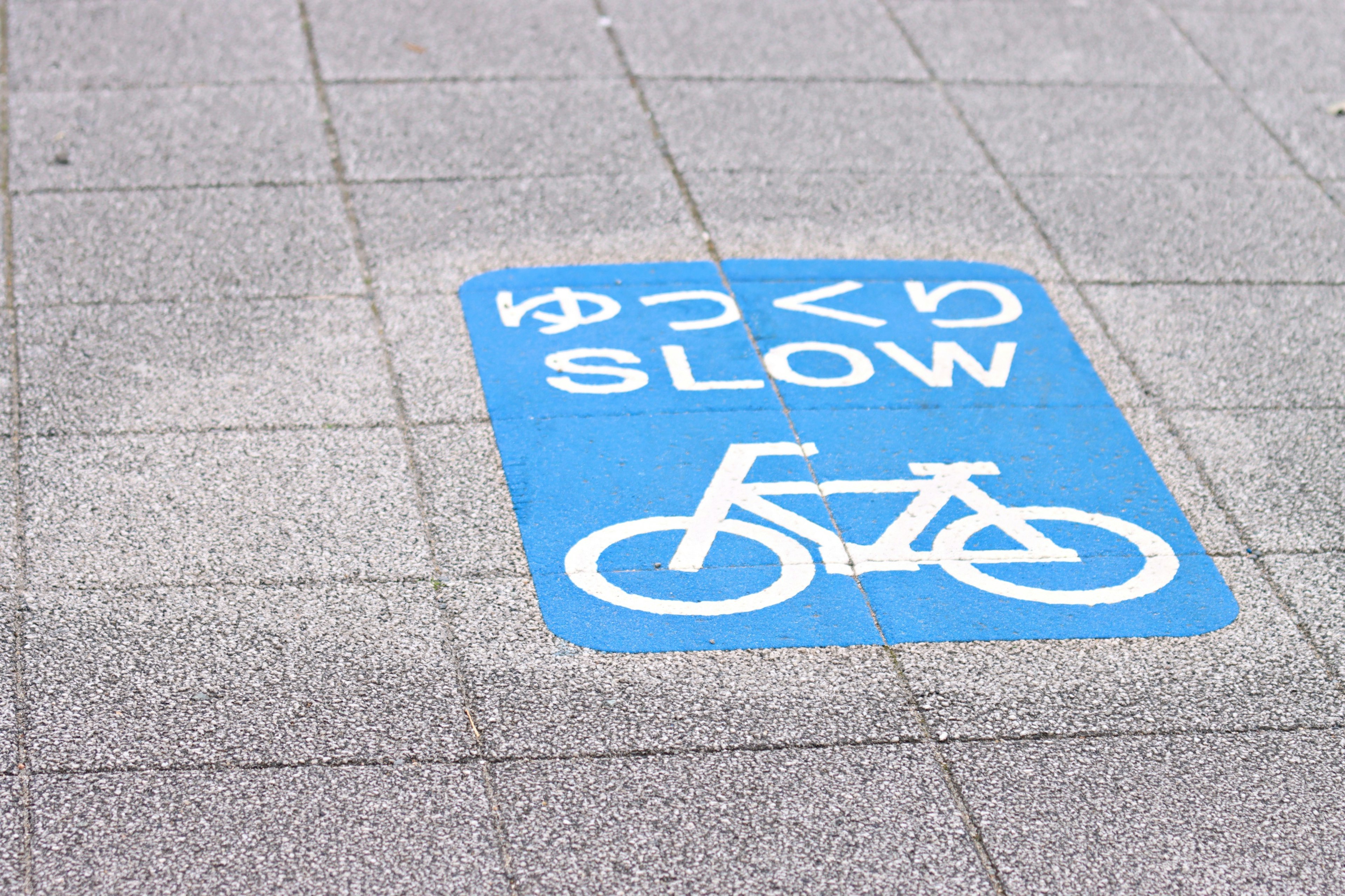 Cartello blu con illustrazione di una bicicletta e le parole 'ゆっくり' e 'SLOW'