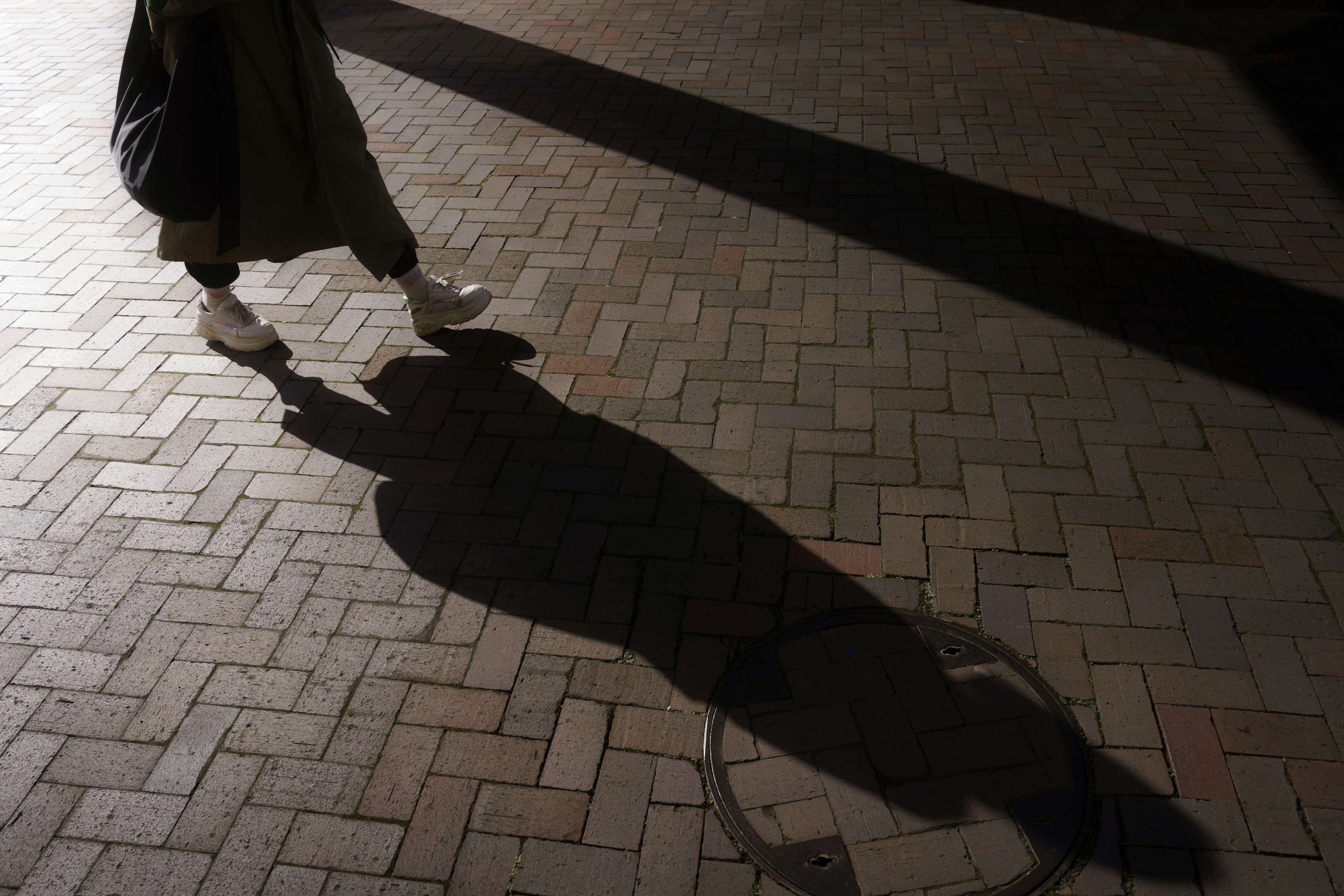 A person's shadow walking on a brick pavement at night