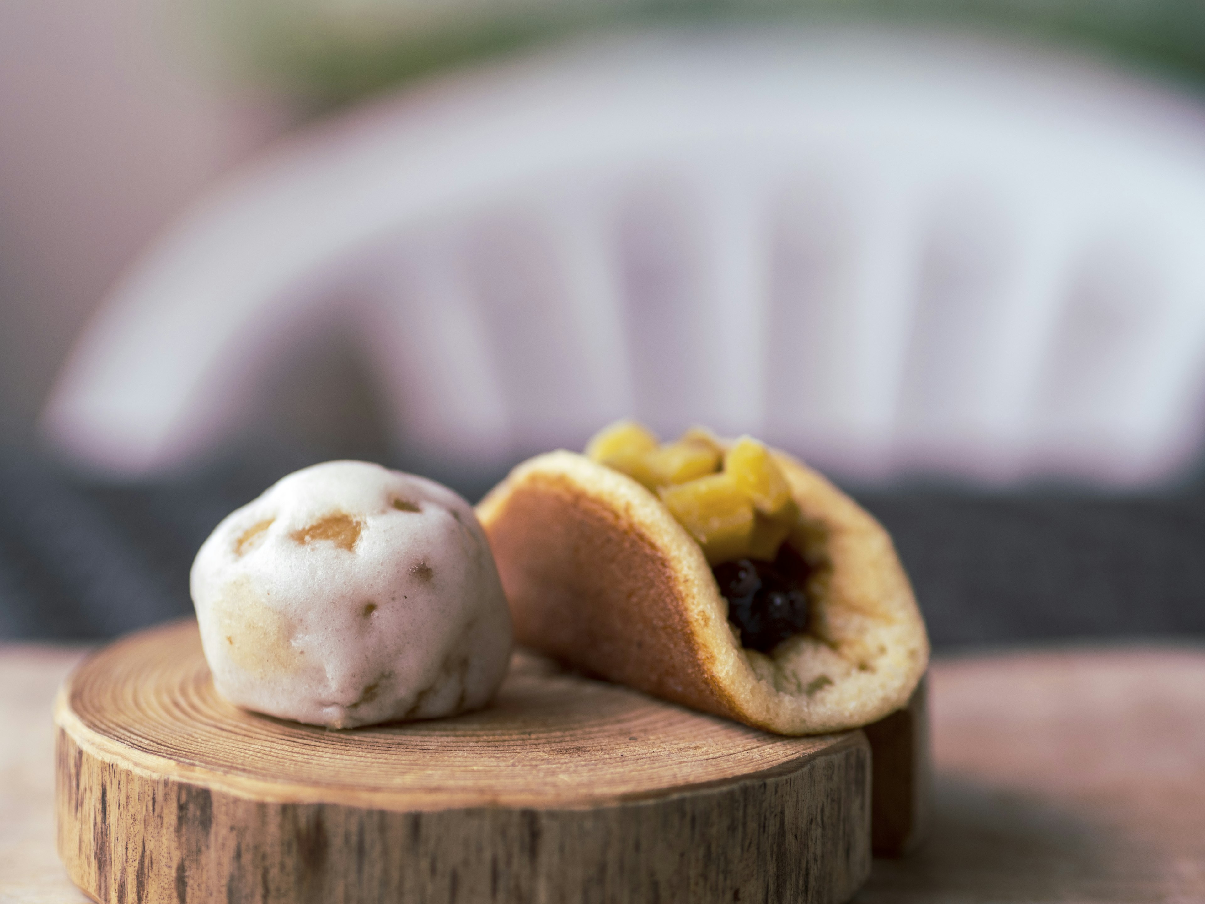 Two types of Japanese sweets on a wooden board One is a round white dumpling The other is a half-moon shaped pastry filled with yellow bean paste