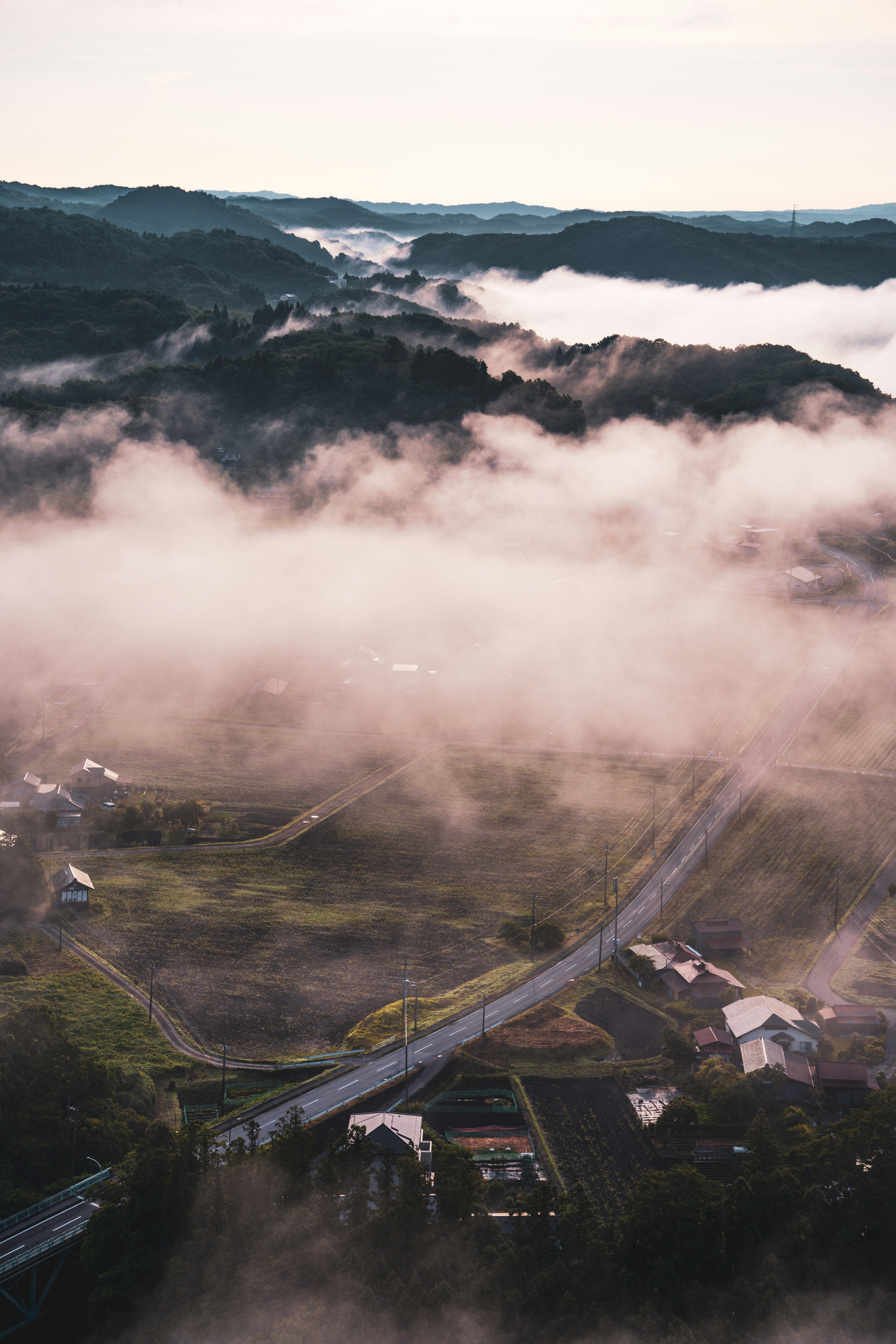 A landscape with hills and a road enveloped in fog