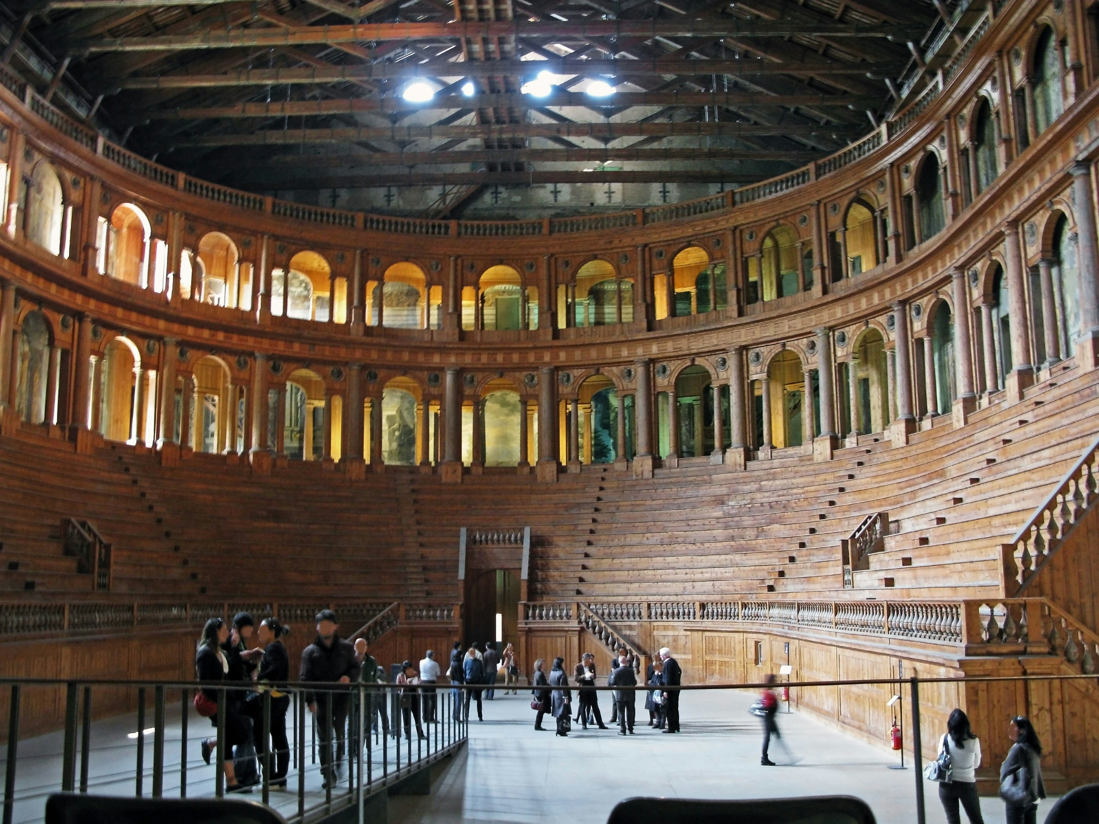 Interno di un anfiteatro circolare con posti a sedere e struttura in legno luce brillante che entra