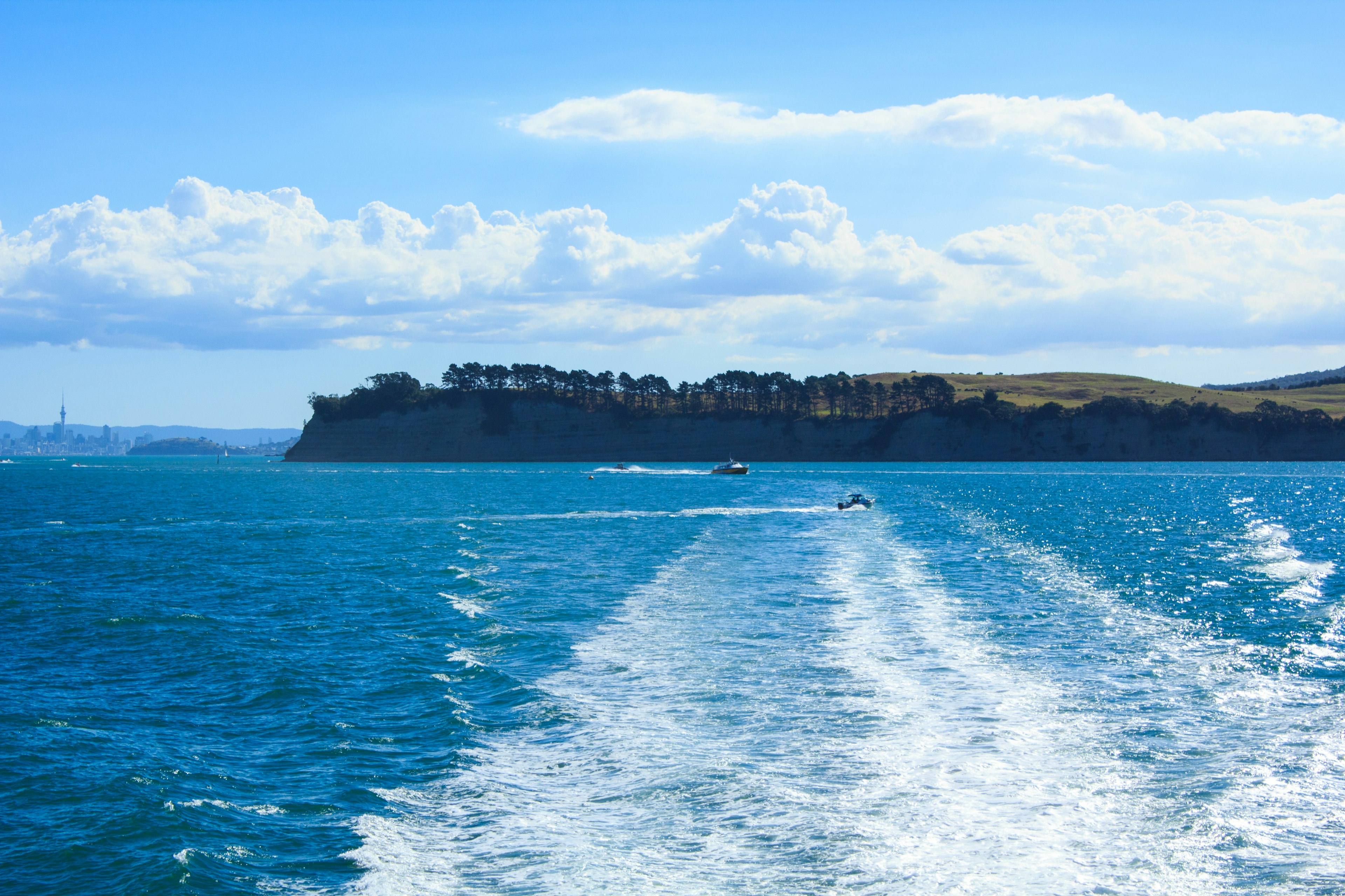 Vista panoramica dell'oceano blu con scie bianche e un'isola lontana