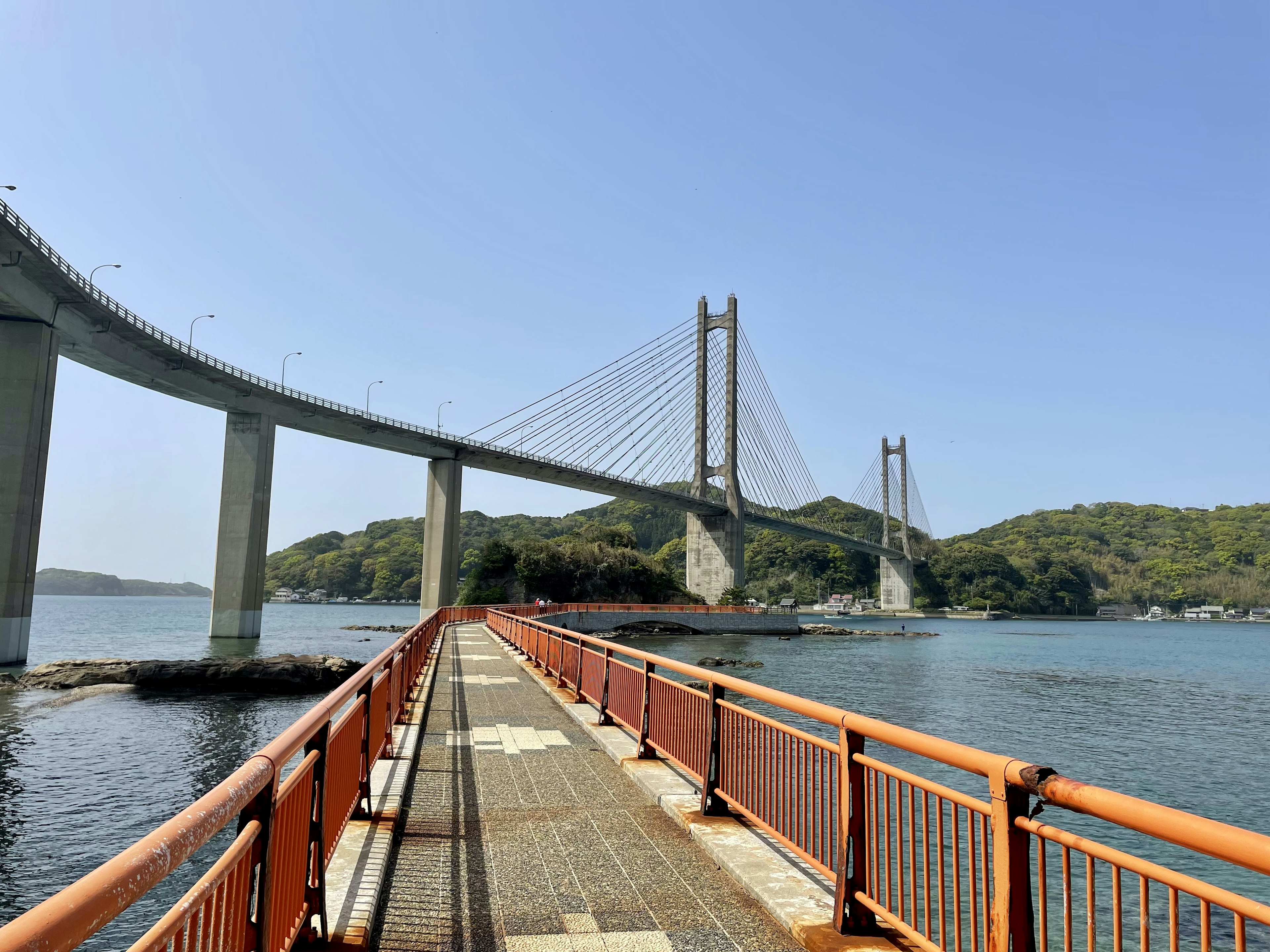 海に架かる橋の美しい風景で、青い空と緑の島が背景にある