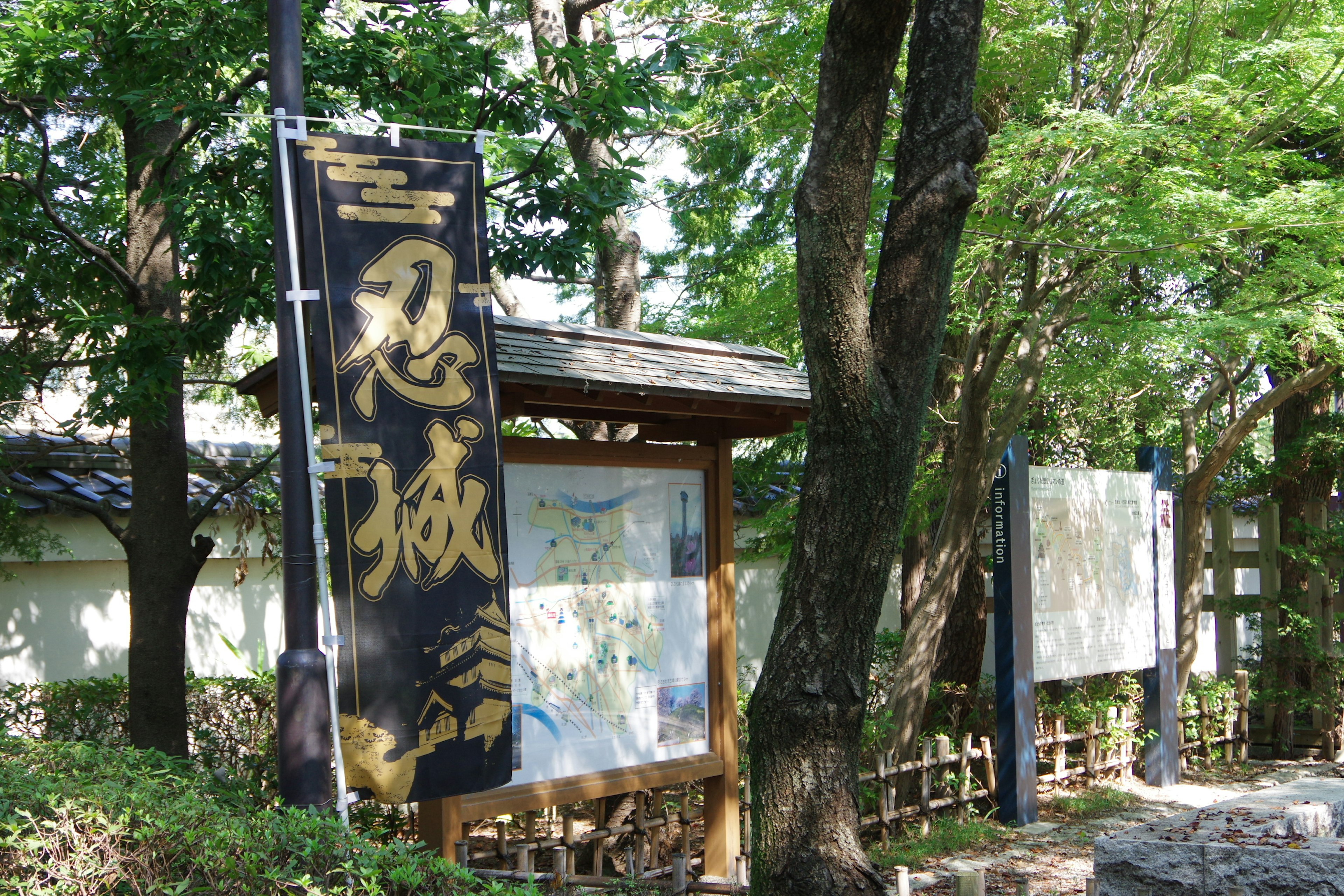 忍城の看板と緑の木々がある風景