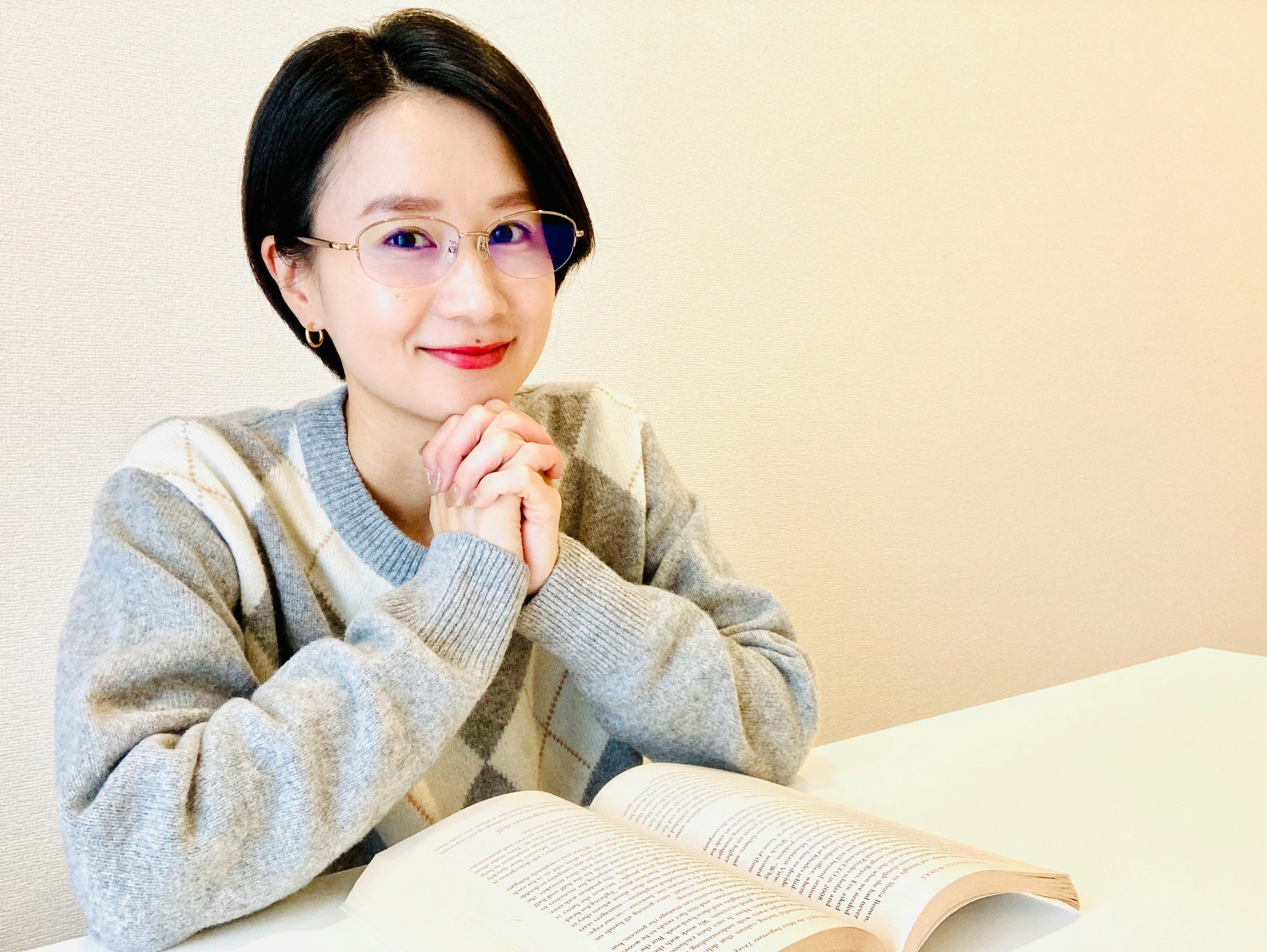 Young woman smiling with hands clasped in front of an open book