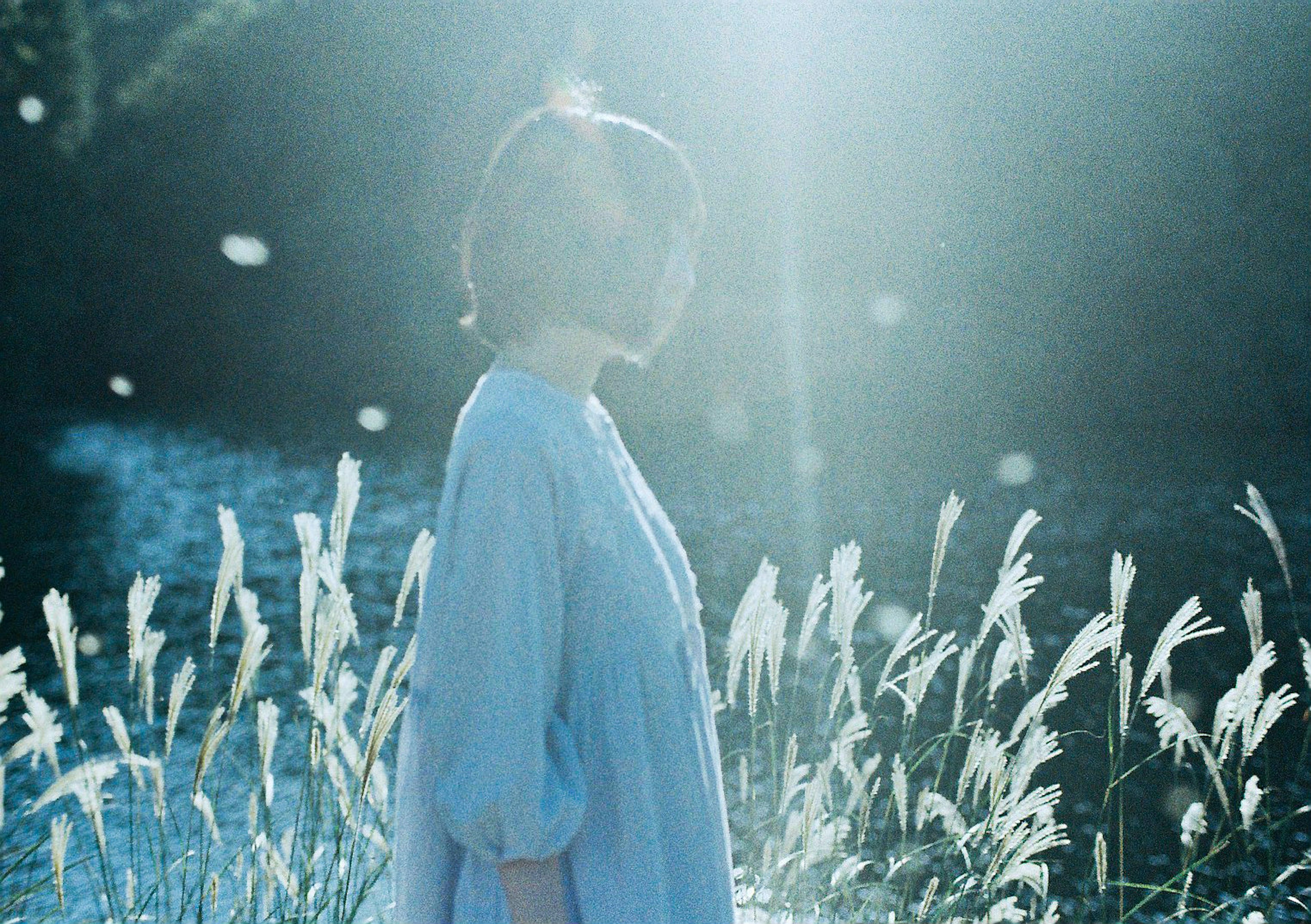 Eine Frau in einem blauen Kleid steht am ruhigen Wasser