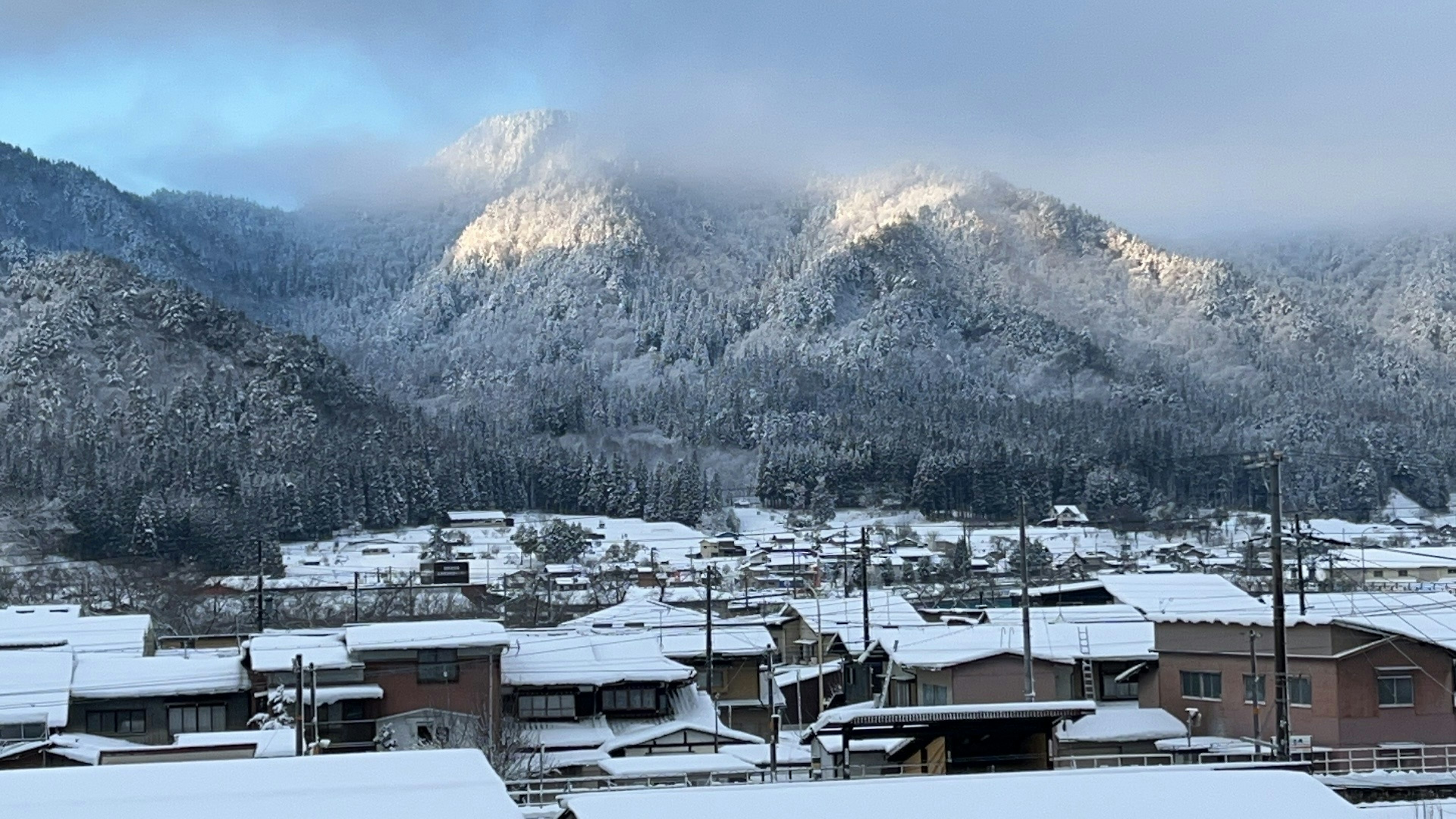 Paisaje de montaña y pueblo cubierto de nieve luz asomando entre las nubes