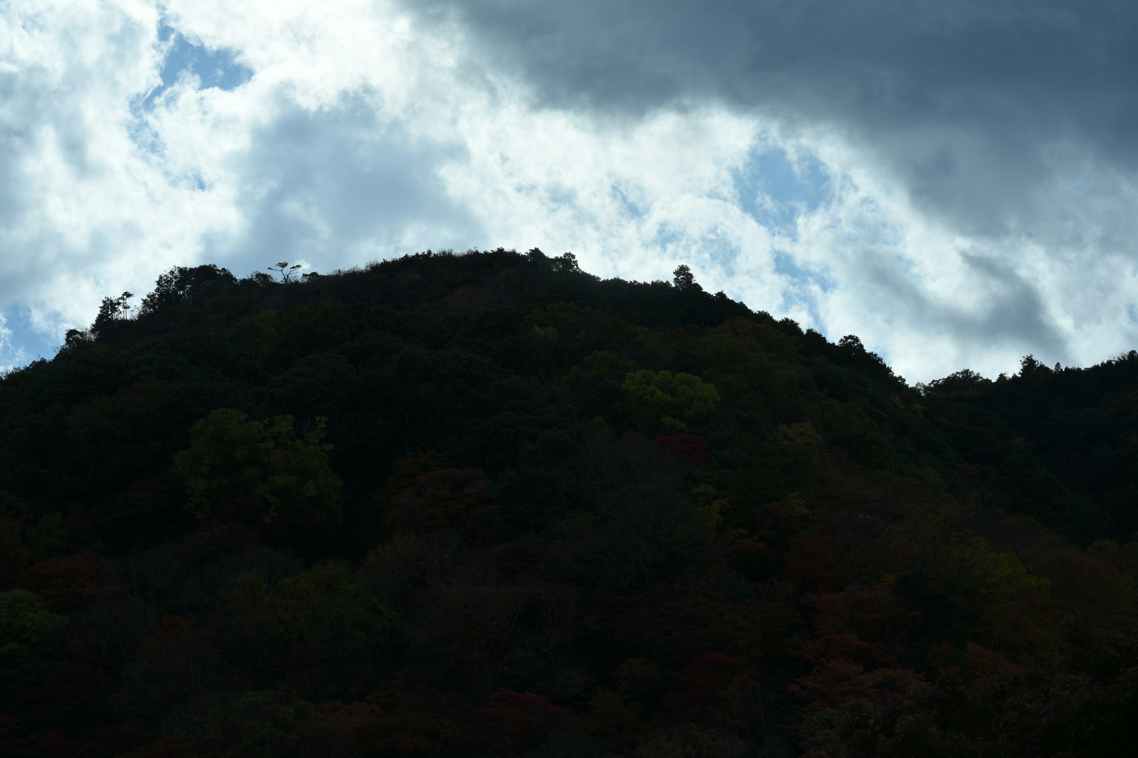 Silhouette di una collina sotto un cielo nuvoloso con colori autunnali