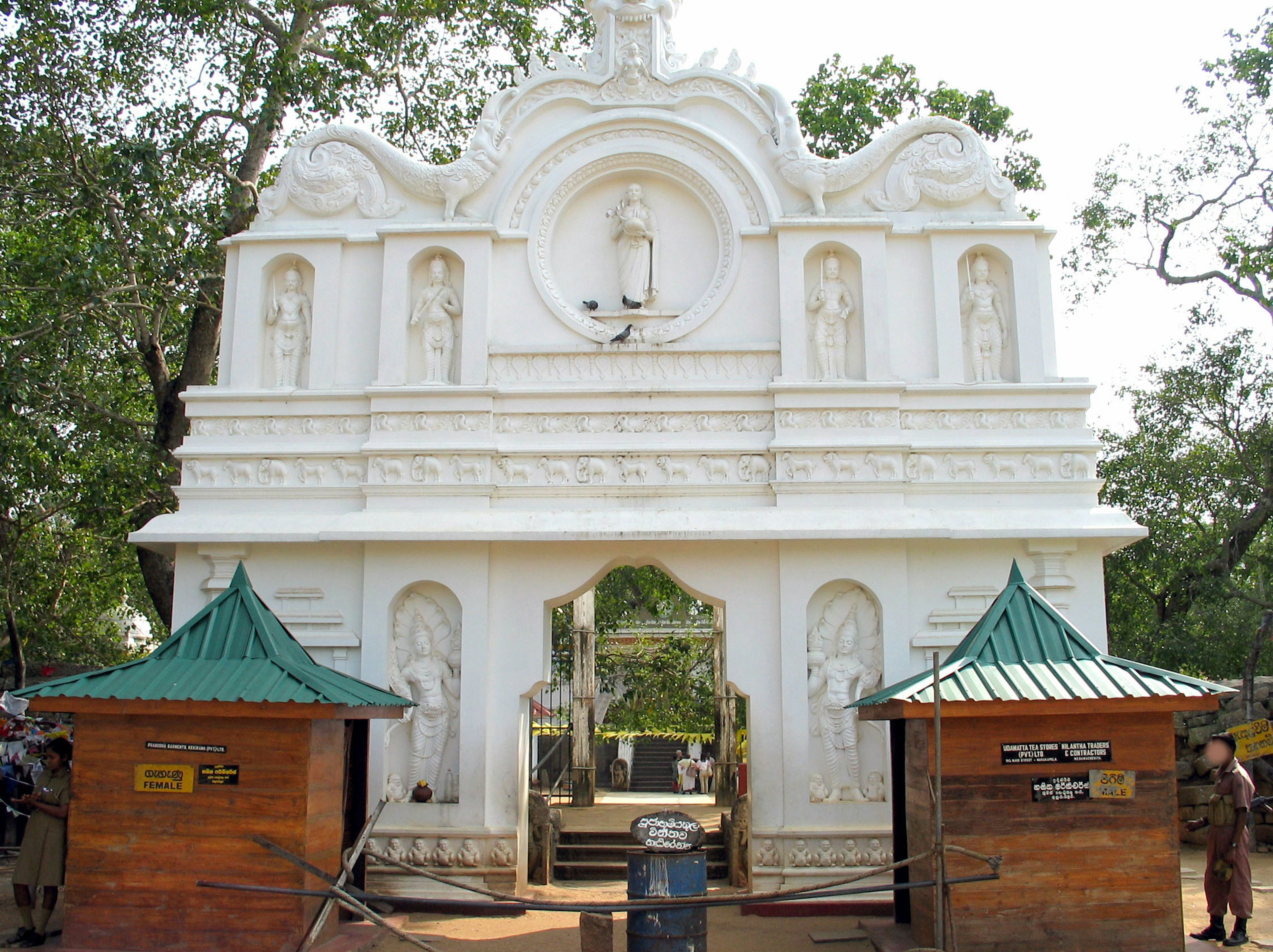 Ingresso di un tempio bianco con pareti scolpite e strutture con tetto verde