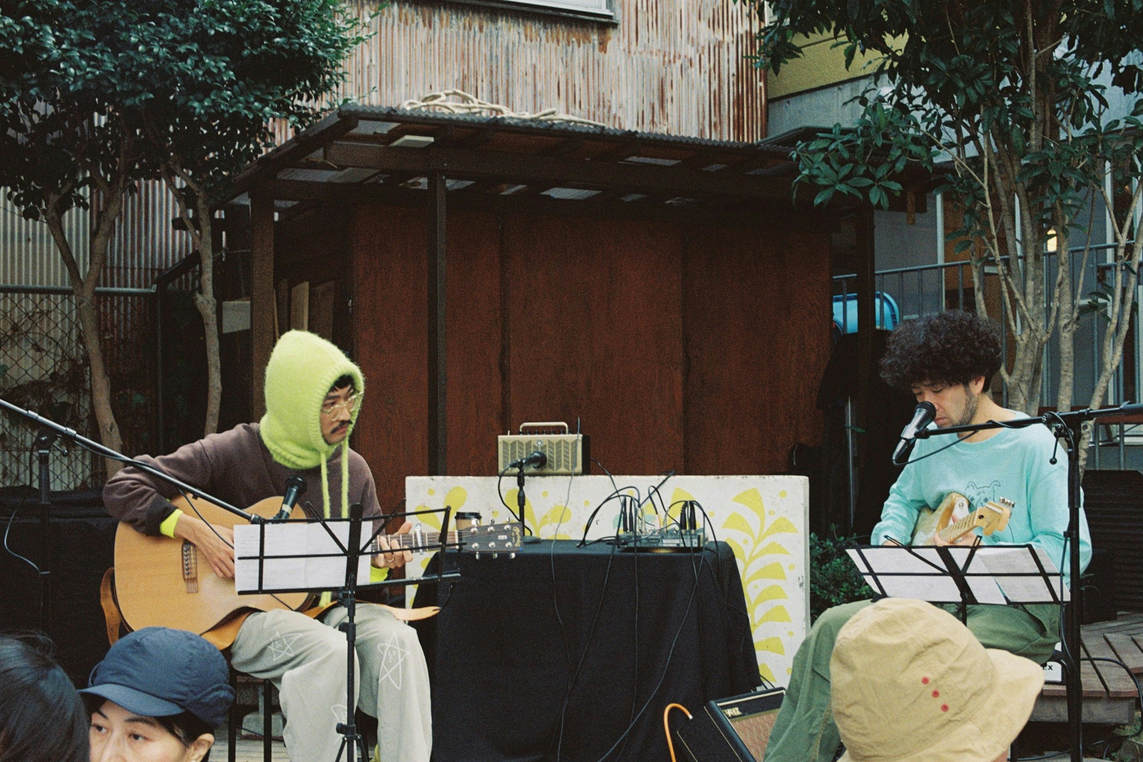 Dua musisi tampil di luar ruangan dengan gitar dan peralatan elektronik