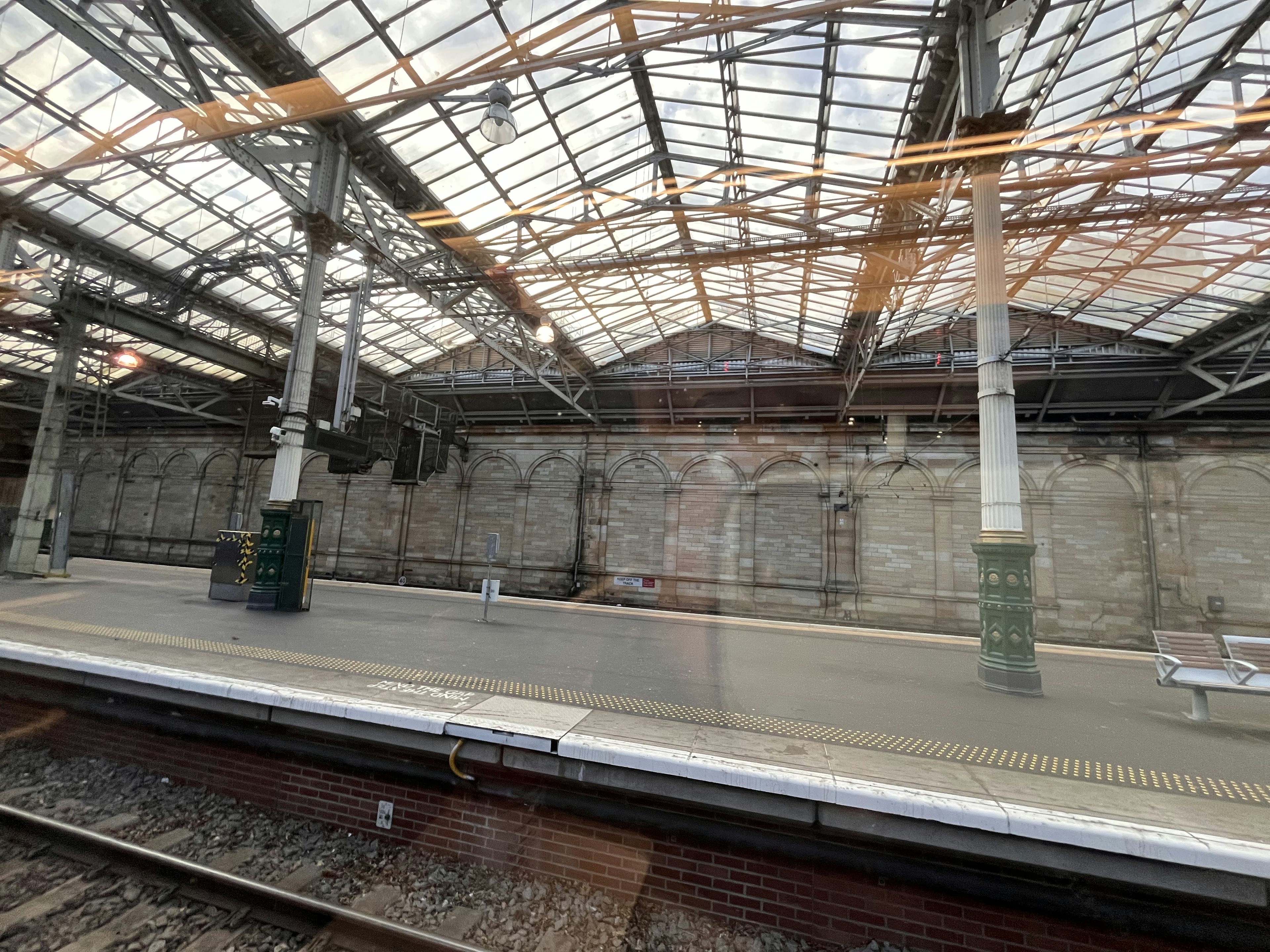 Interior de una vieja estación de tren con una plataforma vacía y un gran techo de vidrio