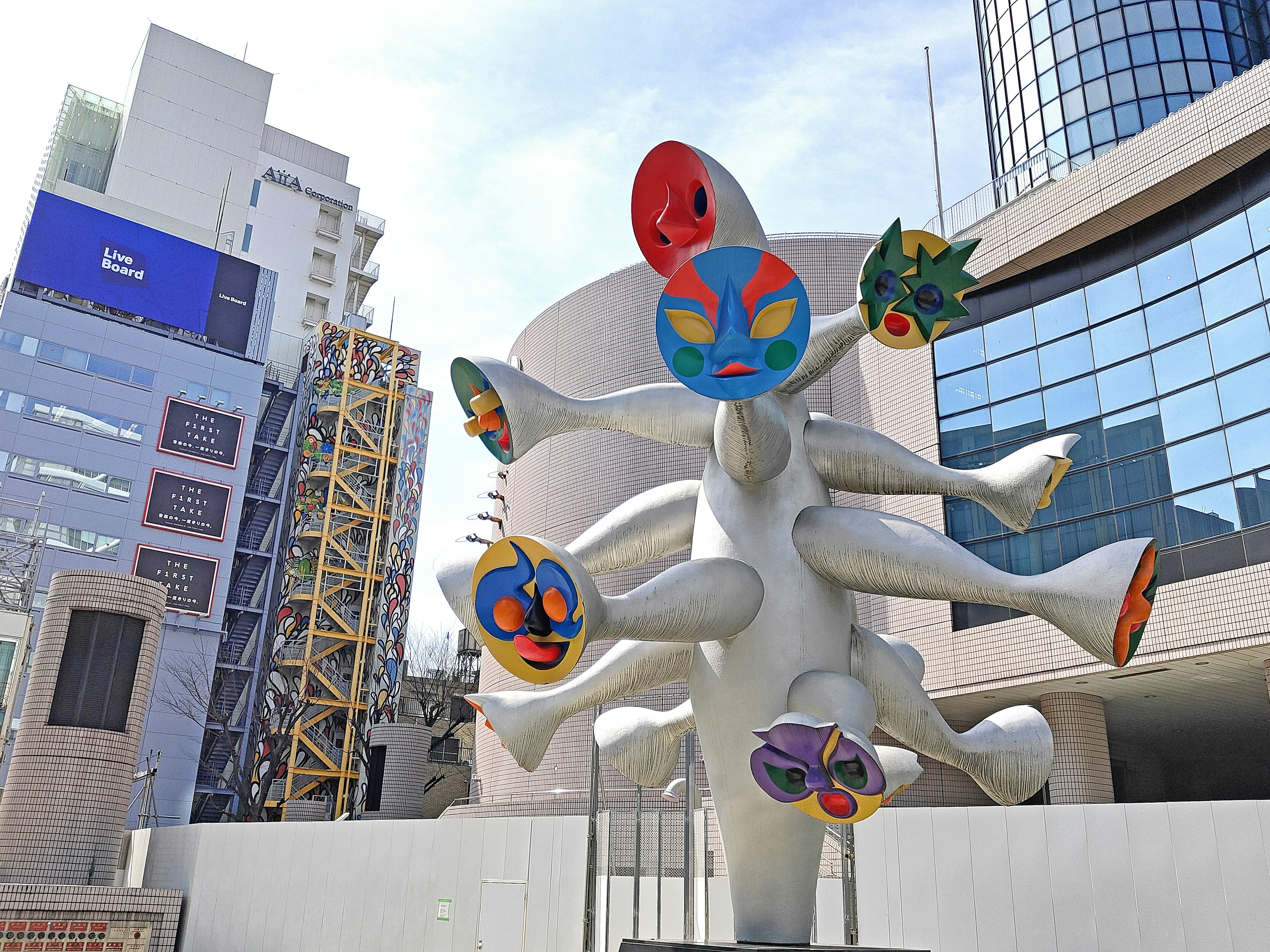 Escultura única con caras coloridas en un entorno urbano