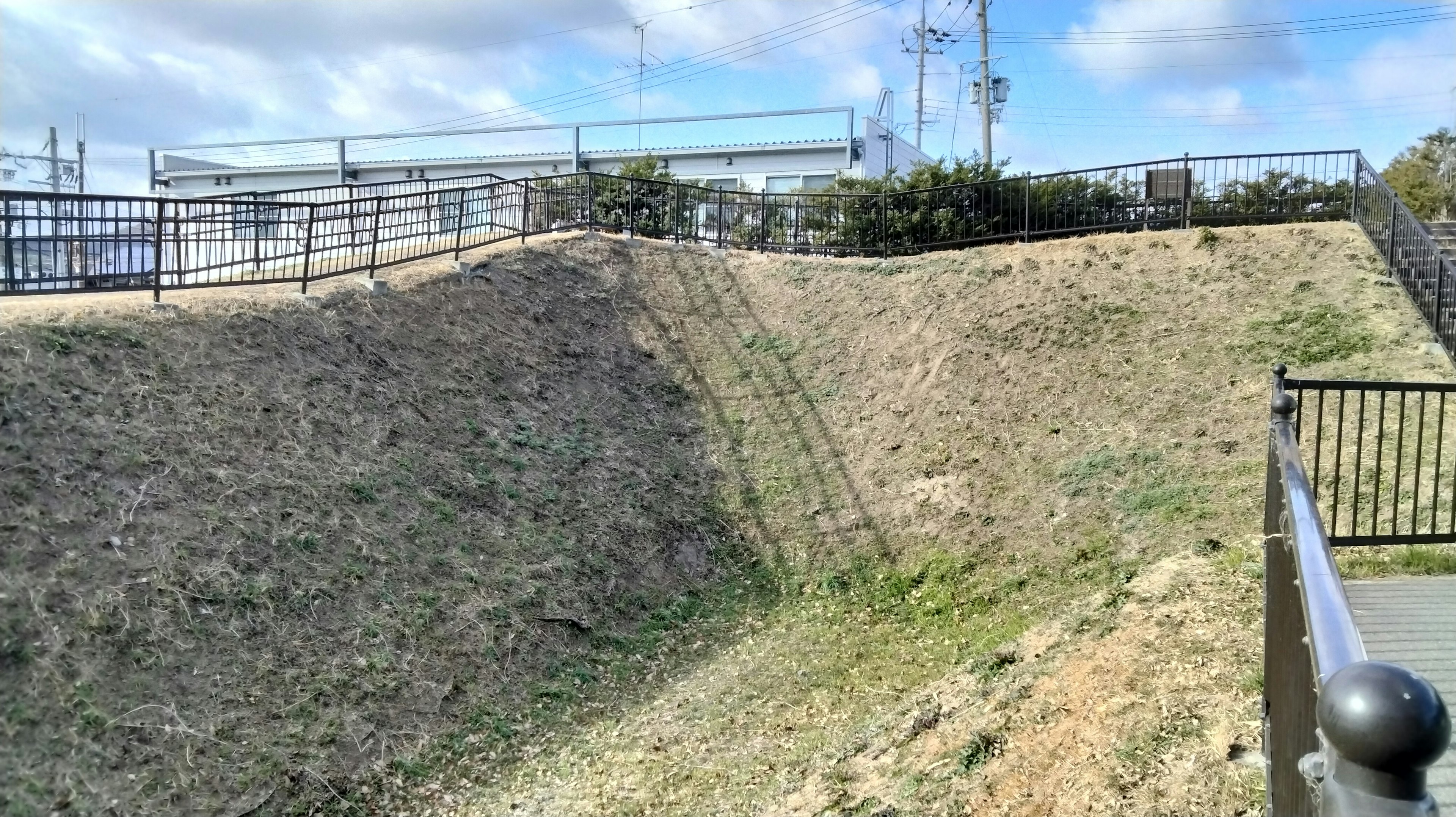 Slope of grass with a fence and power lines in the background