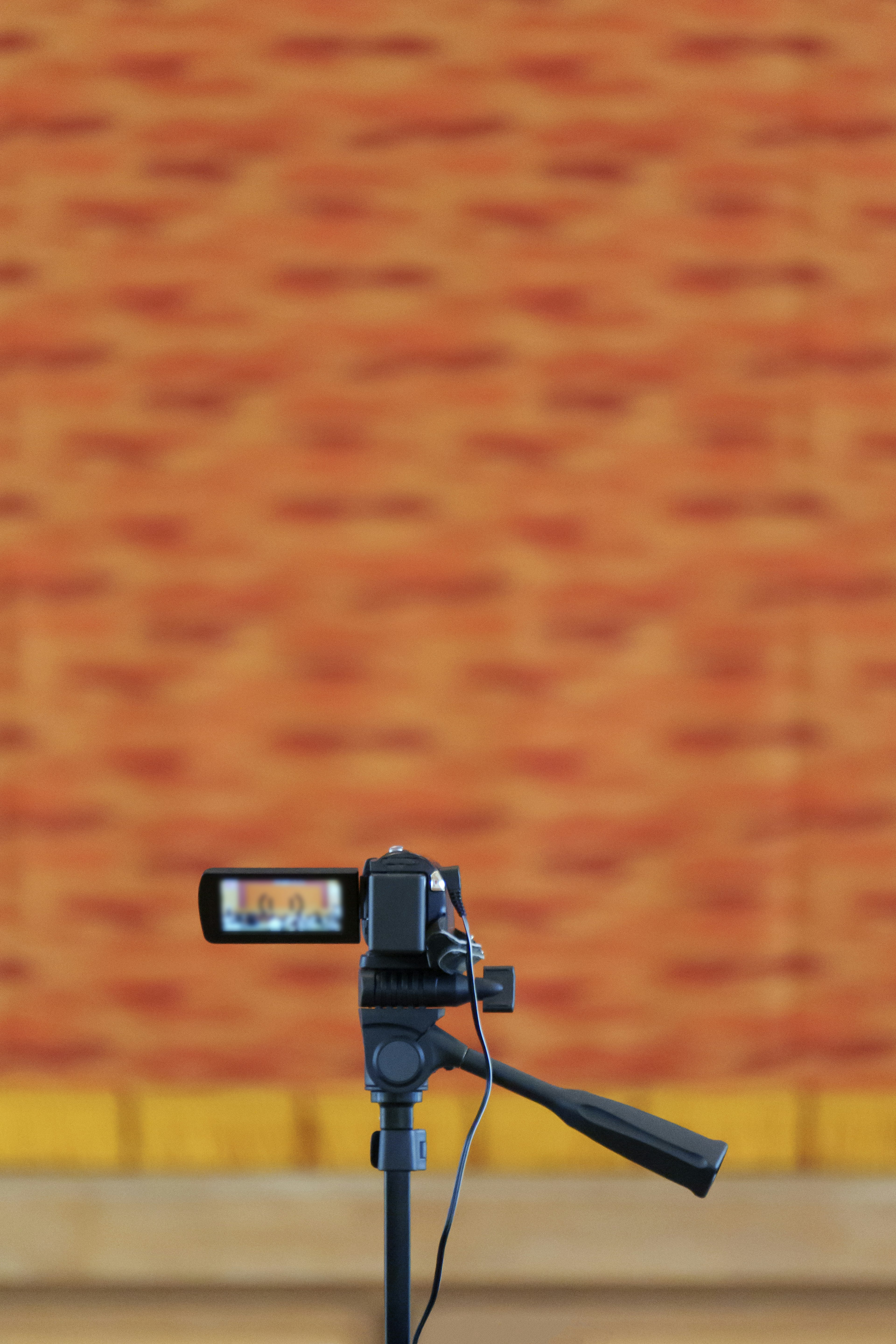 Camera on tripod with an orange textured wall in the background