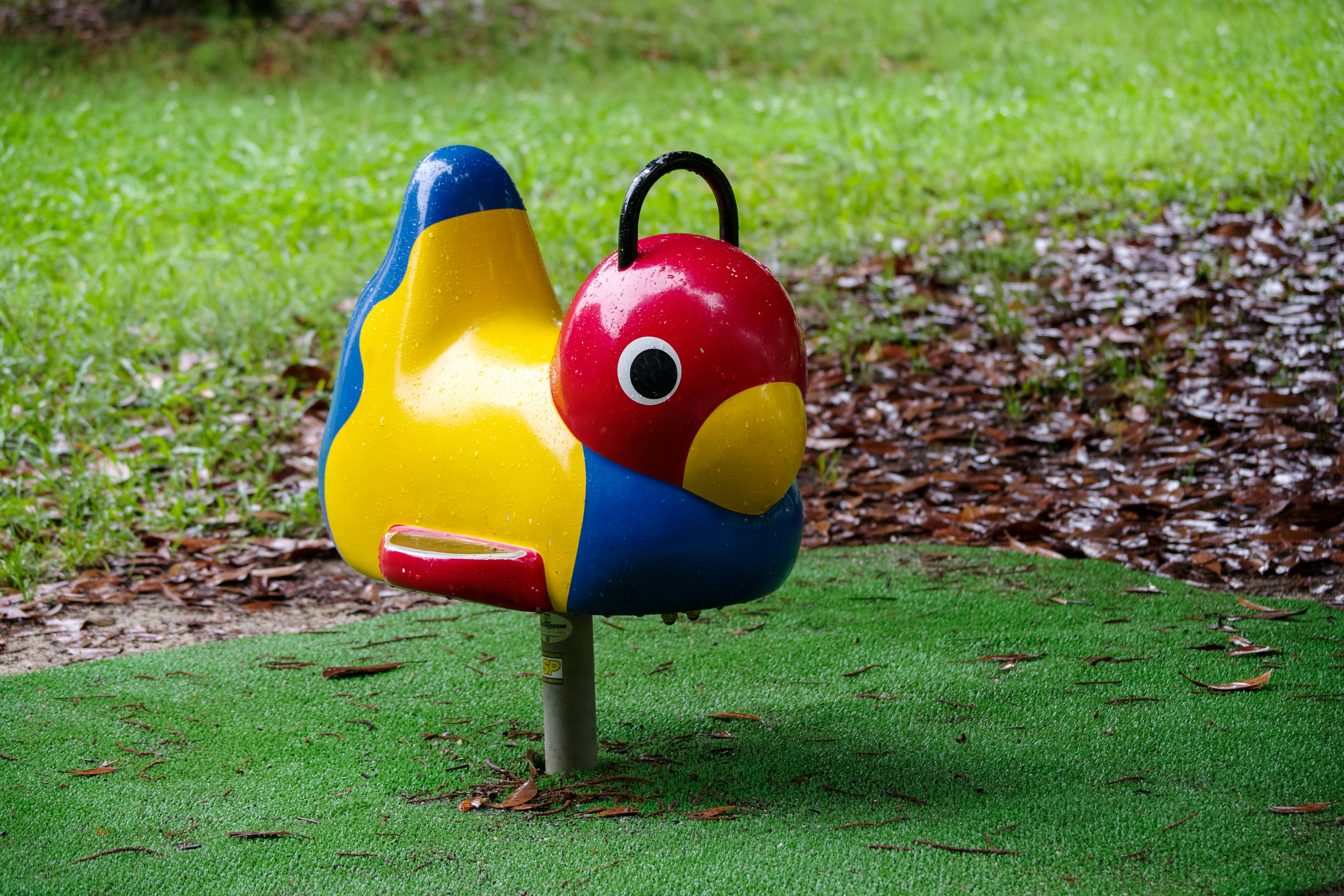 Colorful bird-shaped playground equipment on green grass