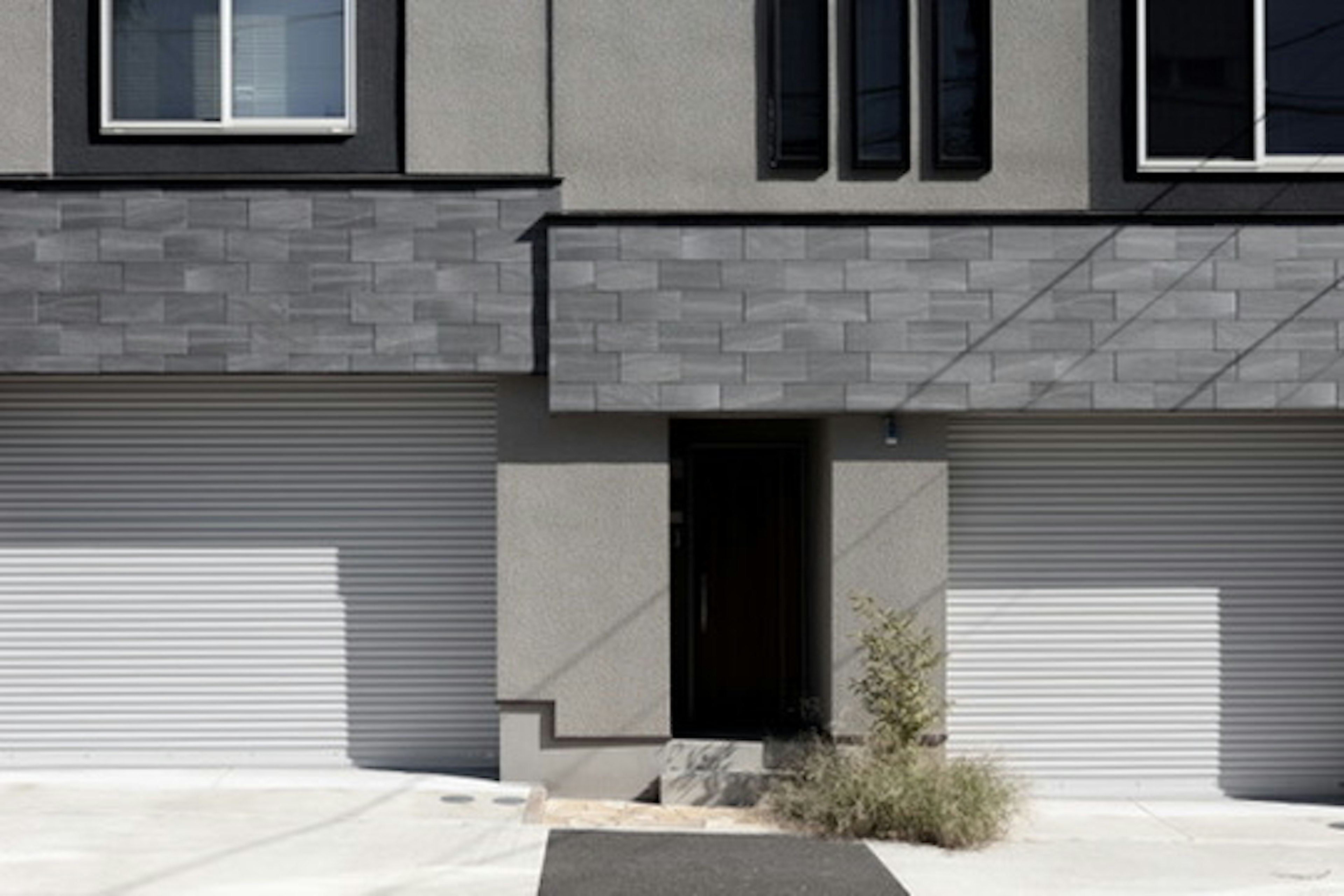 Modern house facade with gray exterior and garage doors