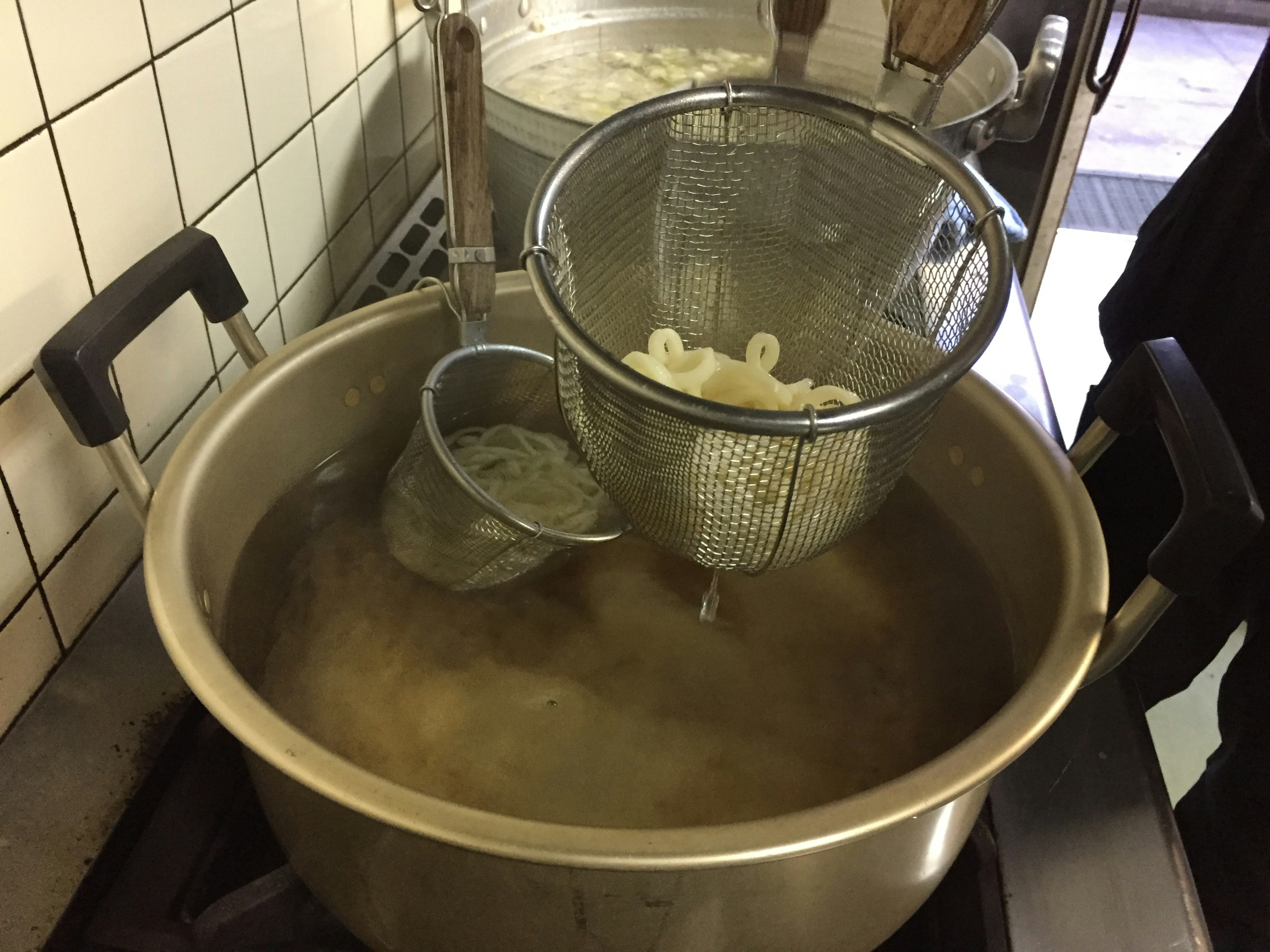 Kitchen scene with a pot boiling ingredients and a strainer