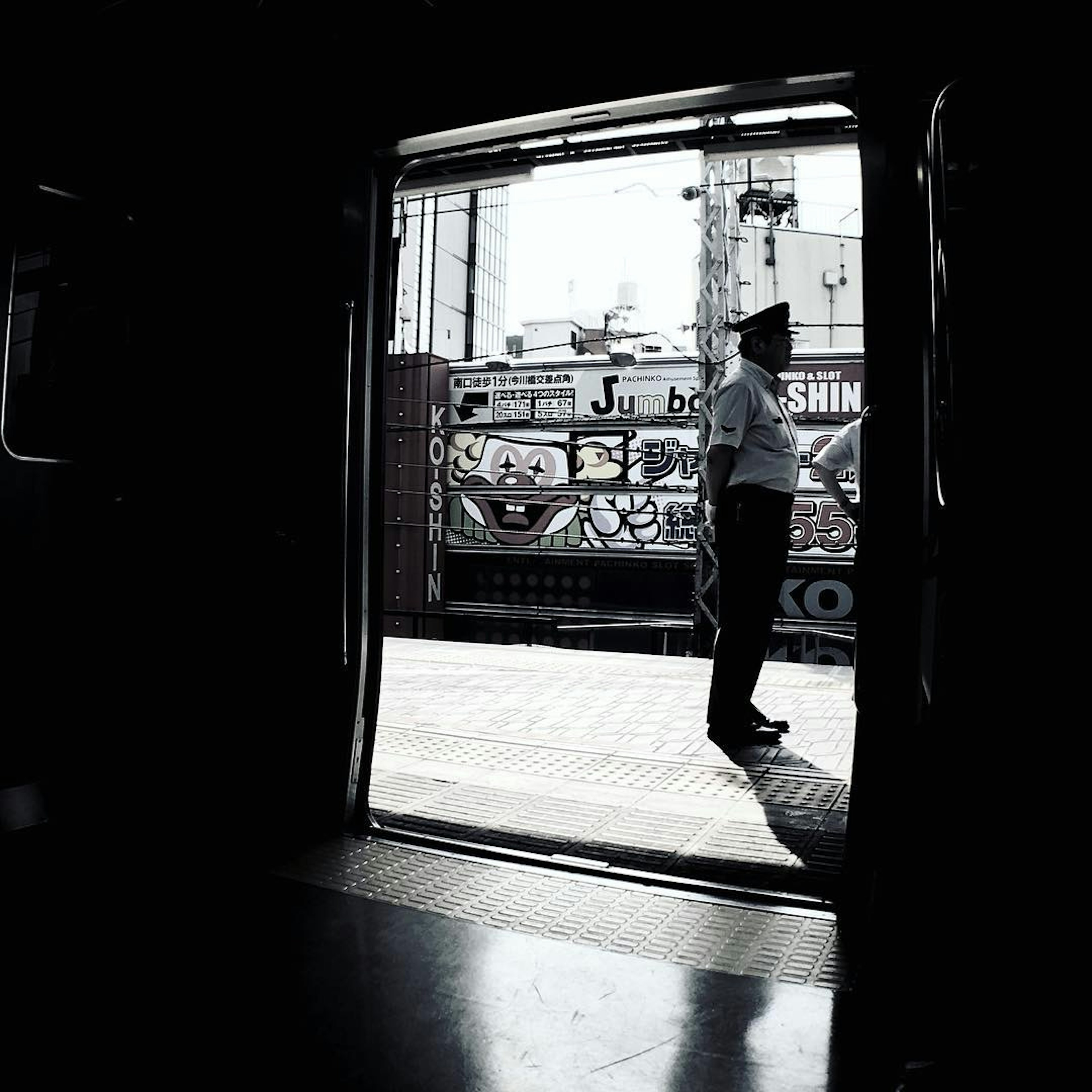 Silhouette of a station attendant standing on a platform with graffiti in the background