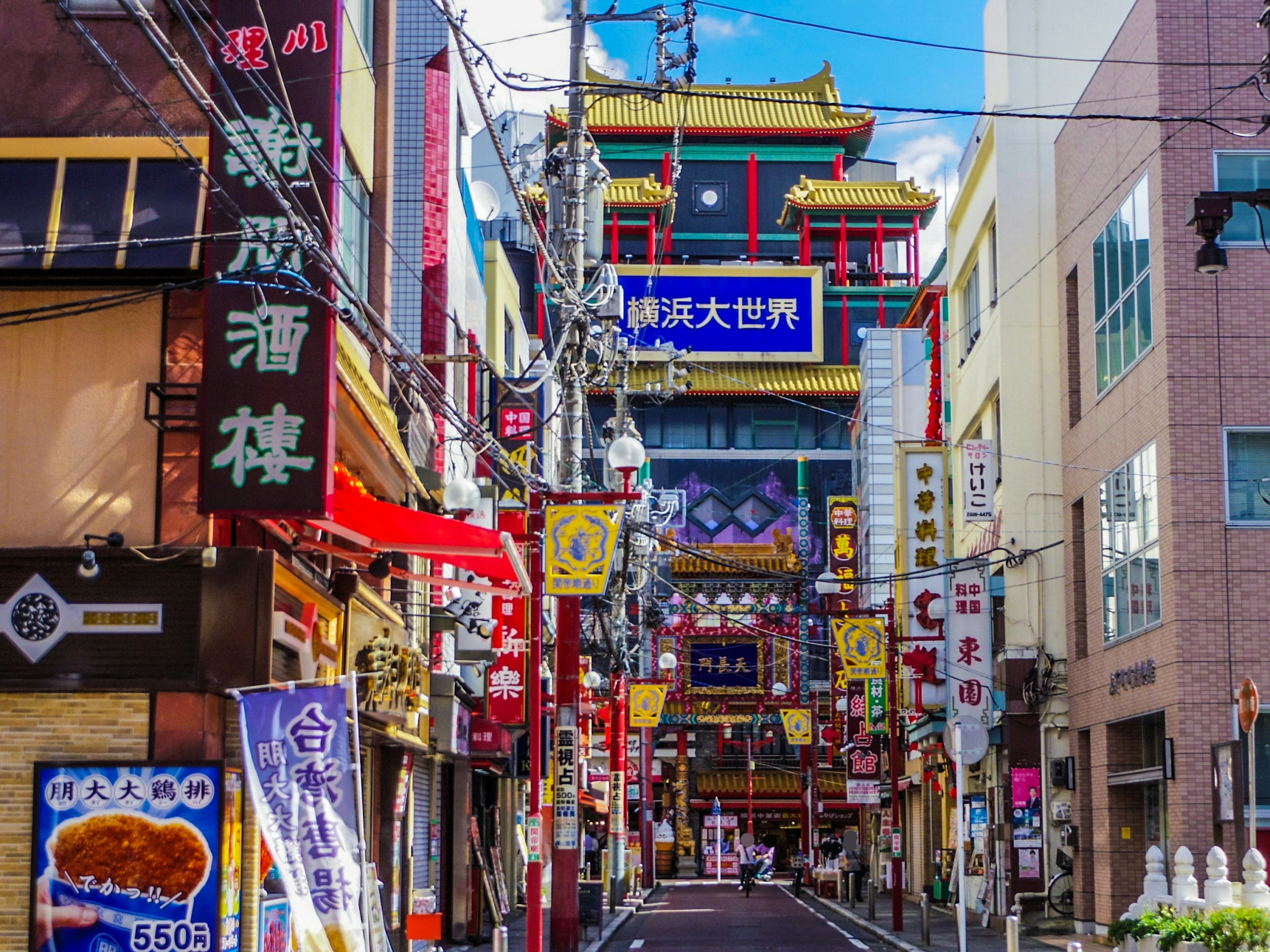 華やかな看板が並ぶ中華街の通りで、青空が広がる