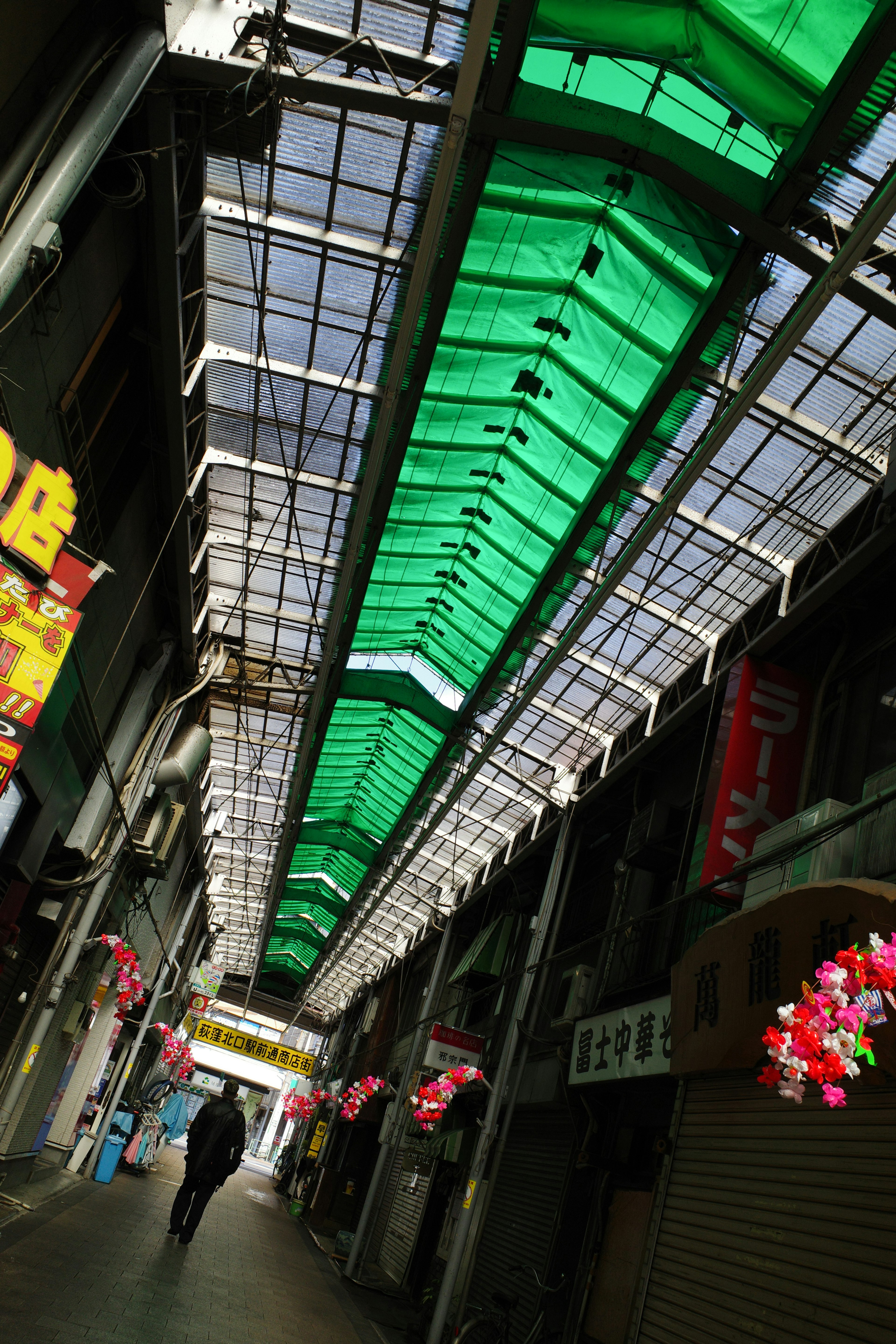 Une rue dans une arcade commerçante avec un toit vert photographiée d'un angle bas