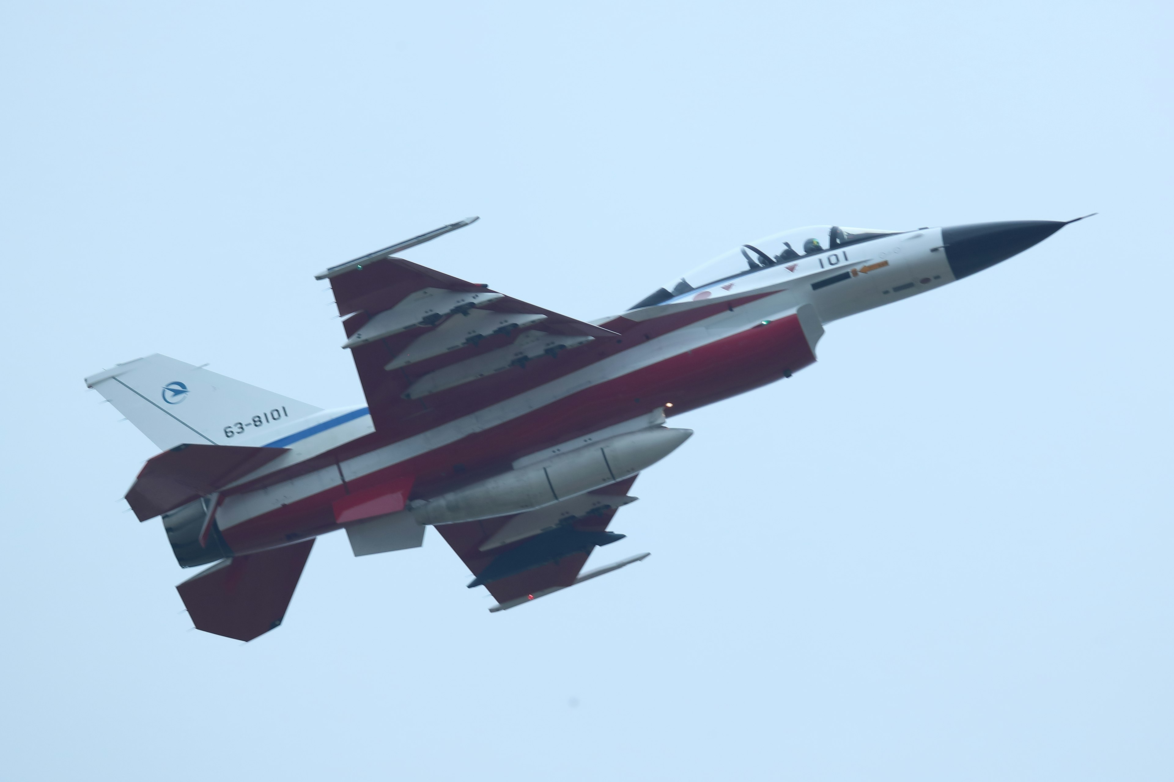 Un jet de chasse avec des marques rouges et blanches monte dans le ciel