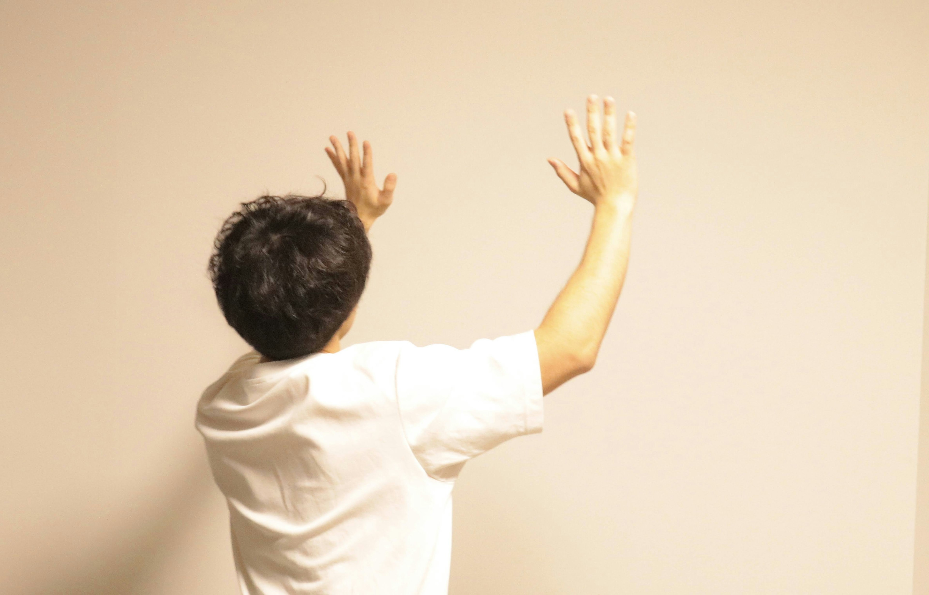 Person raising hands towards a blank wall