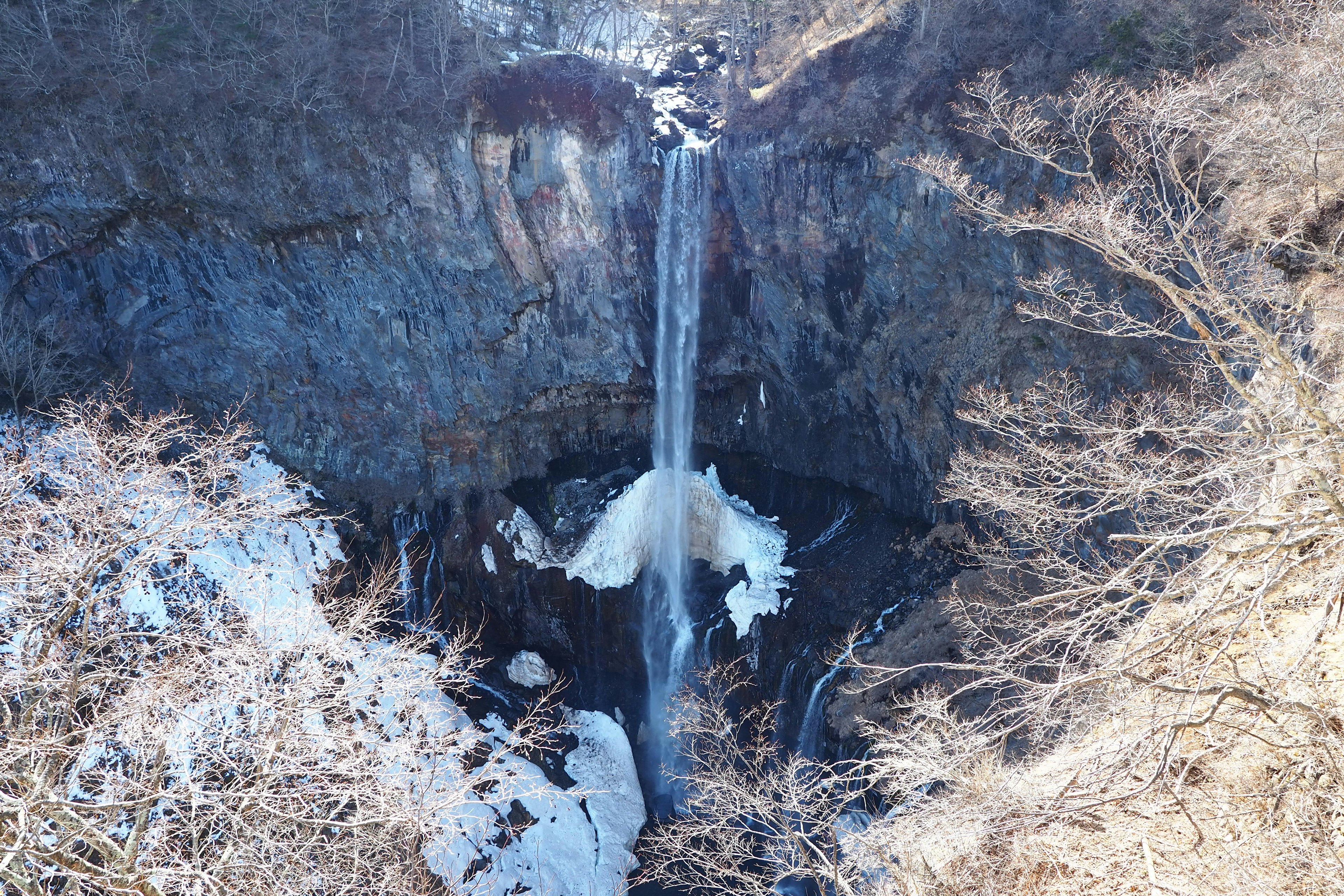 Aerial view of a winter waterfall with frozen ice and surrounding trees