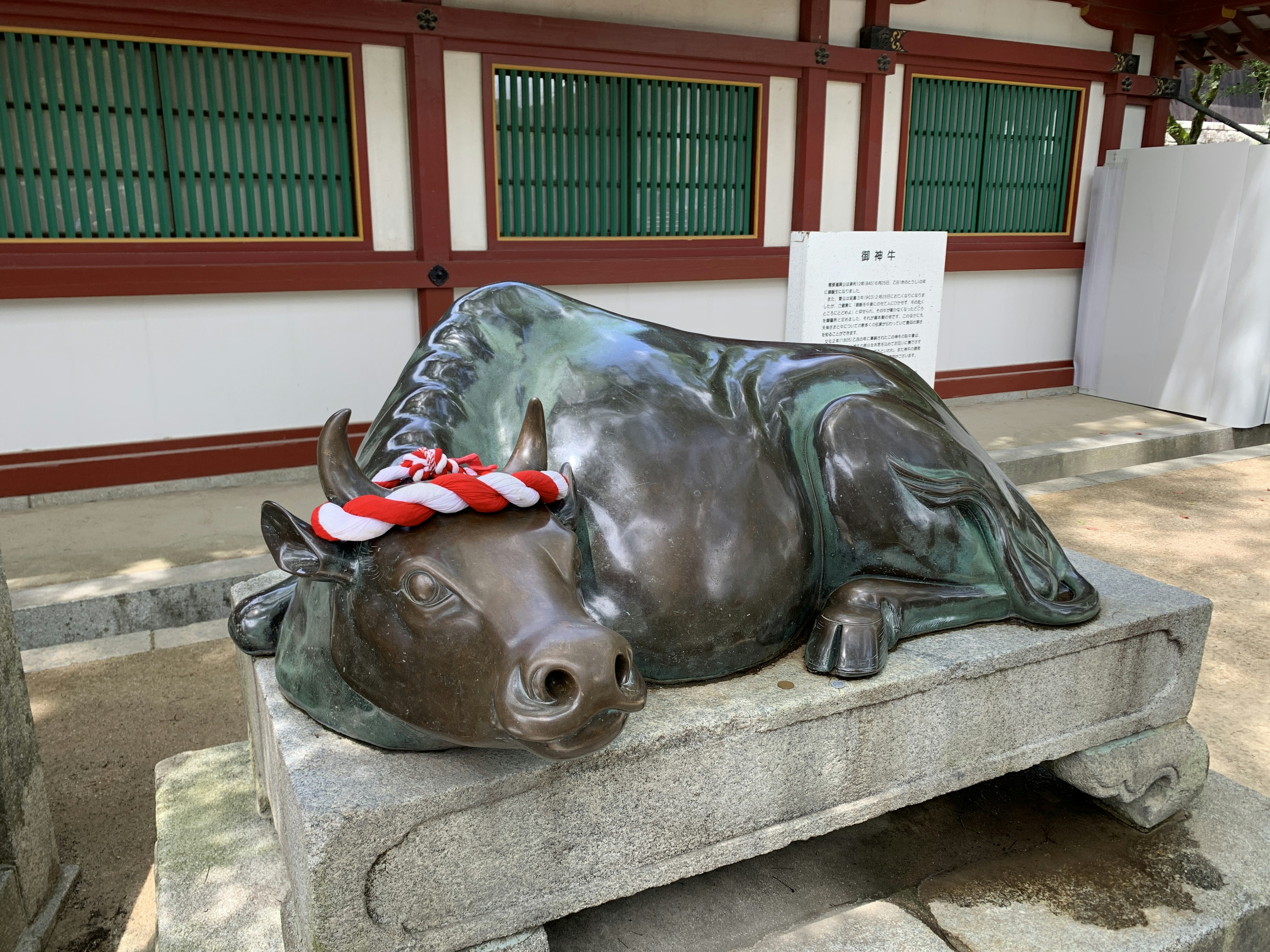 Bronze statue of a sleeping bull wearing a red striped hat