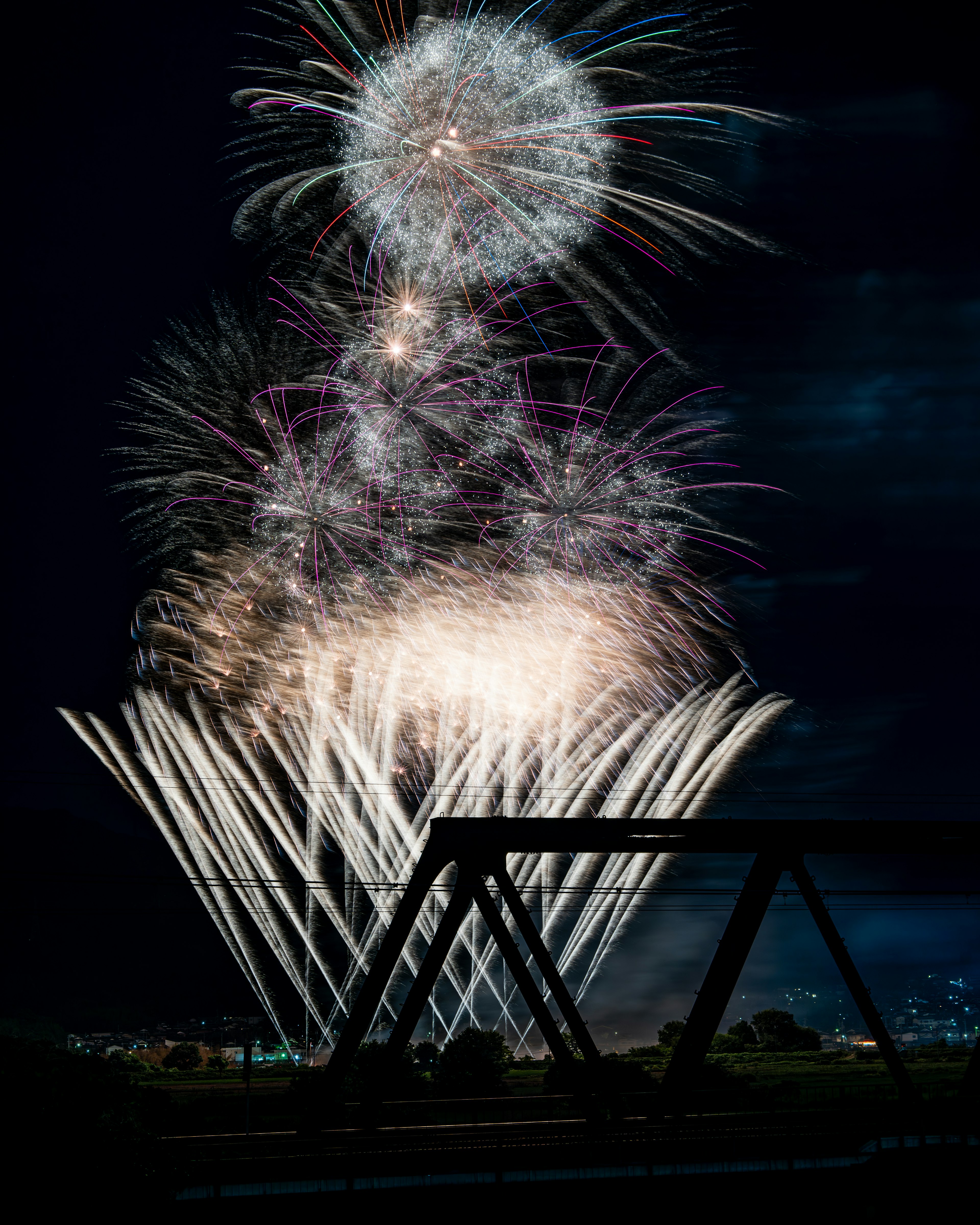 Splendido spettacolo di fuochi d'artificio nel cielo notturno con la silhouette di un ponte in metallo