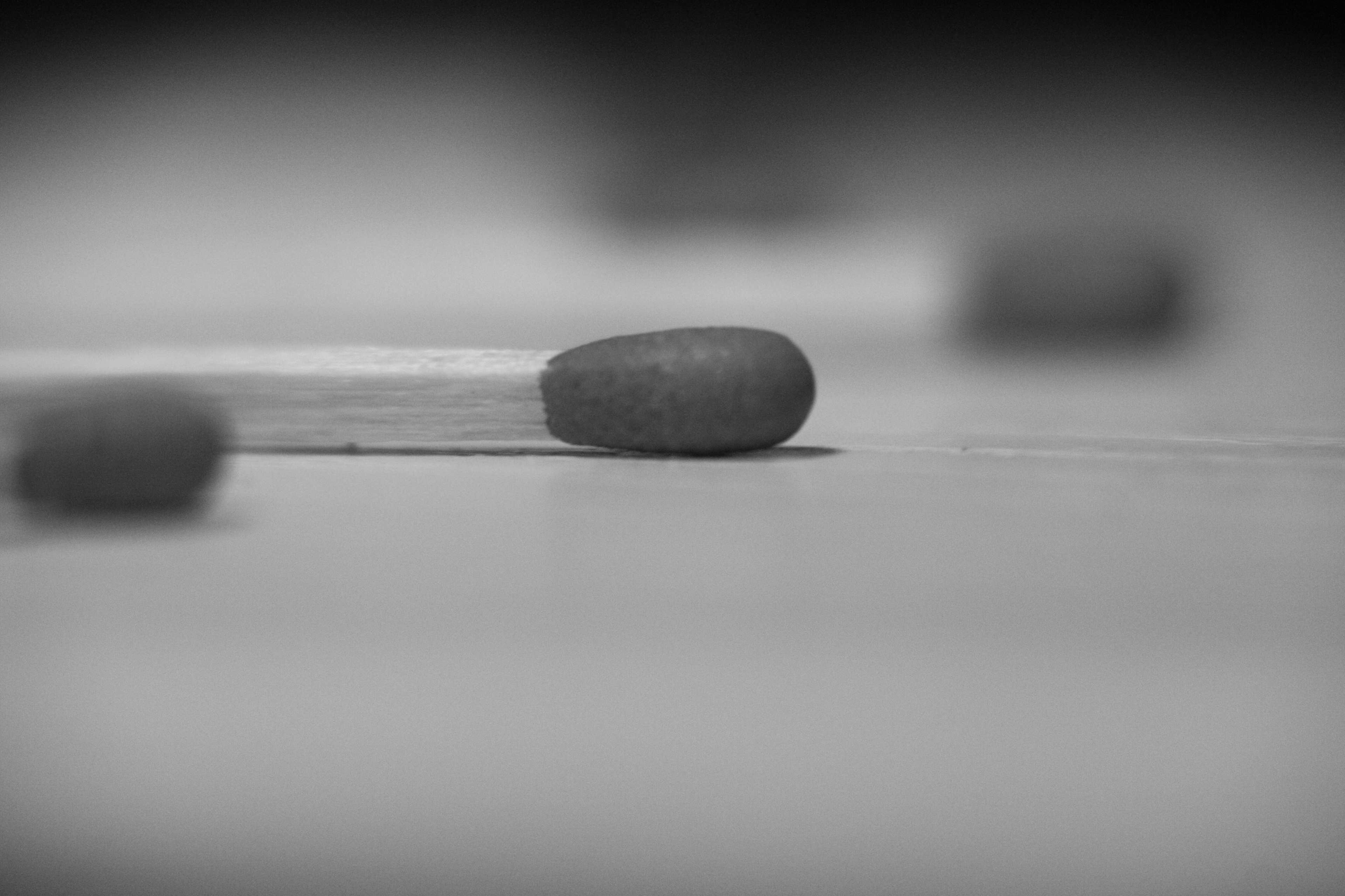 Imagen en primer plano de un fósforo en blanco y negro con un palo de madera y una cabeza de fósforo roja