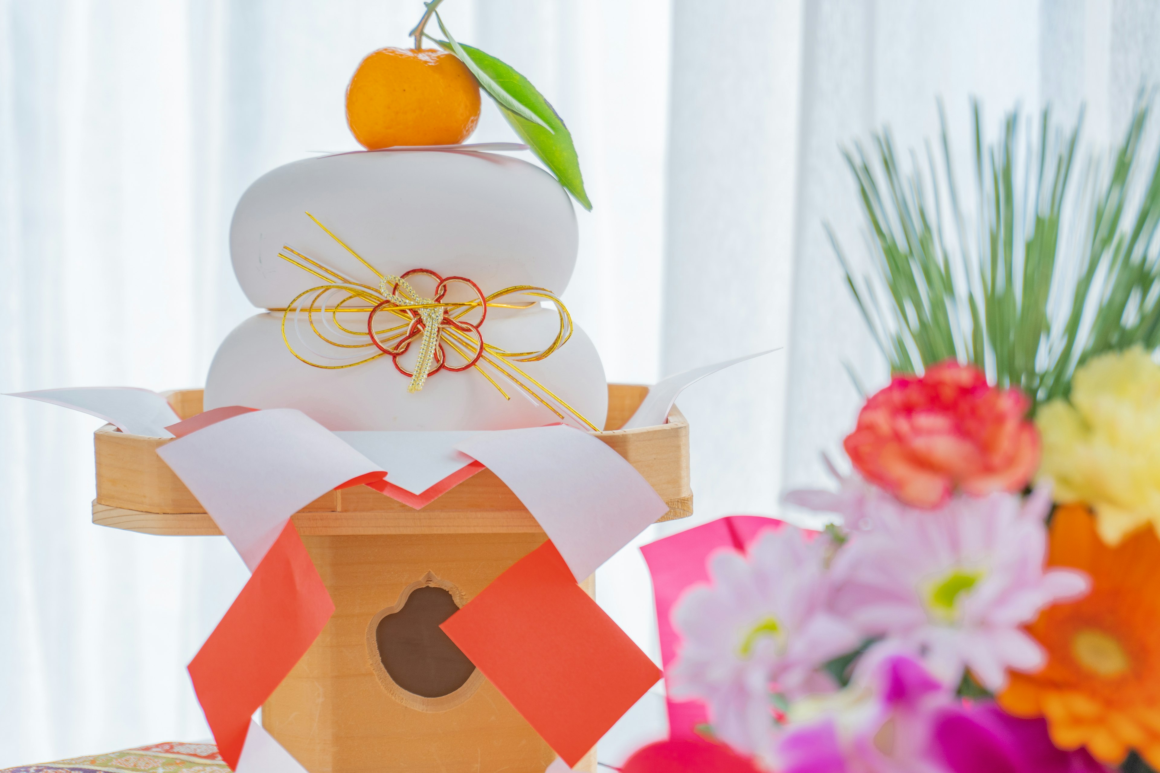 Kagamimochi japonés tradicional exhibido con flores vibrantes