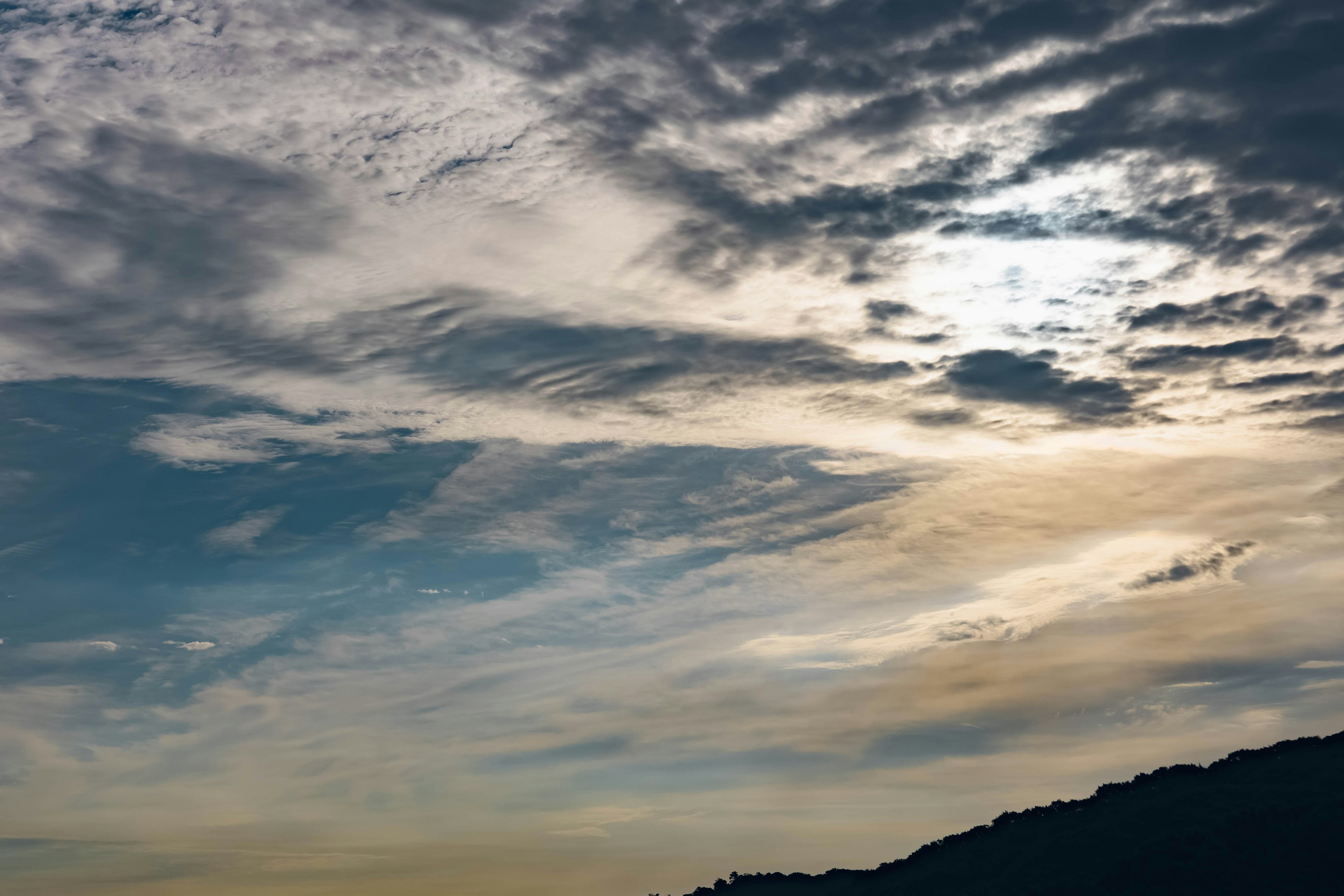 Wolken in einem blauen Himmel mit der Silhouette eines Berges