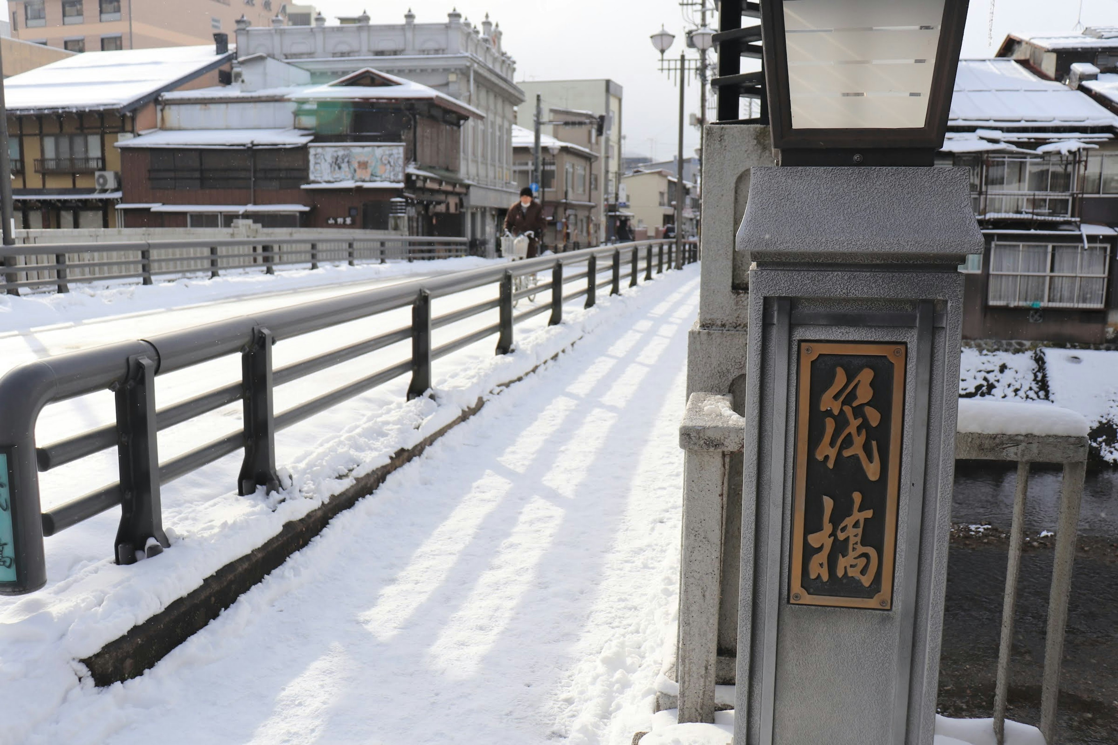 View of a snow-covered bridge area with traditional buildings