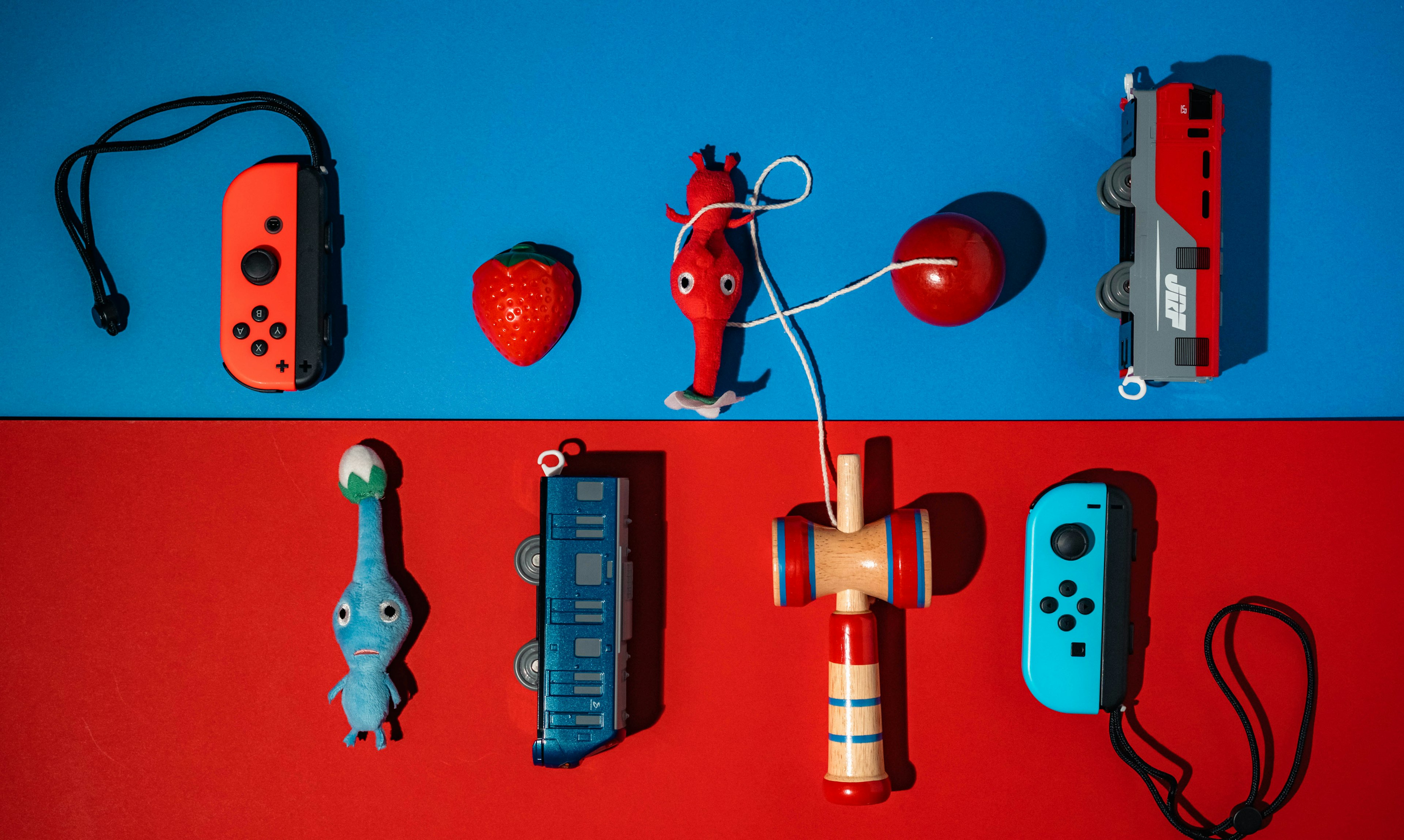 Game controllers and toy characters arranged on a blue and red background