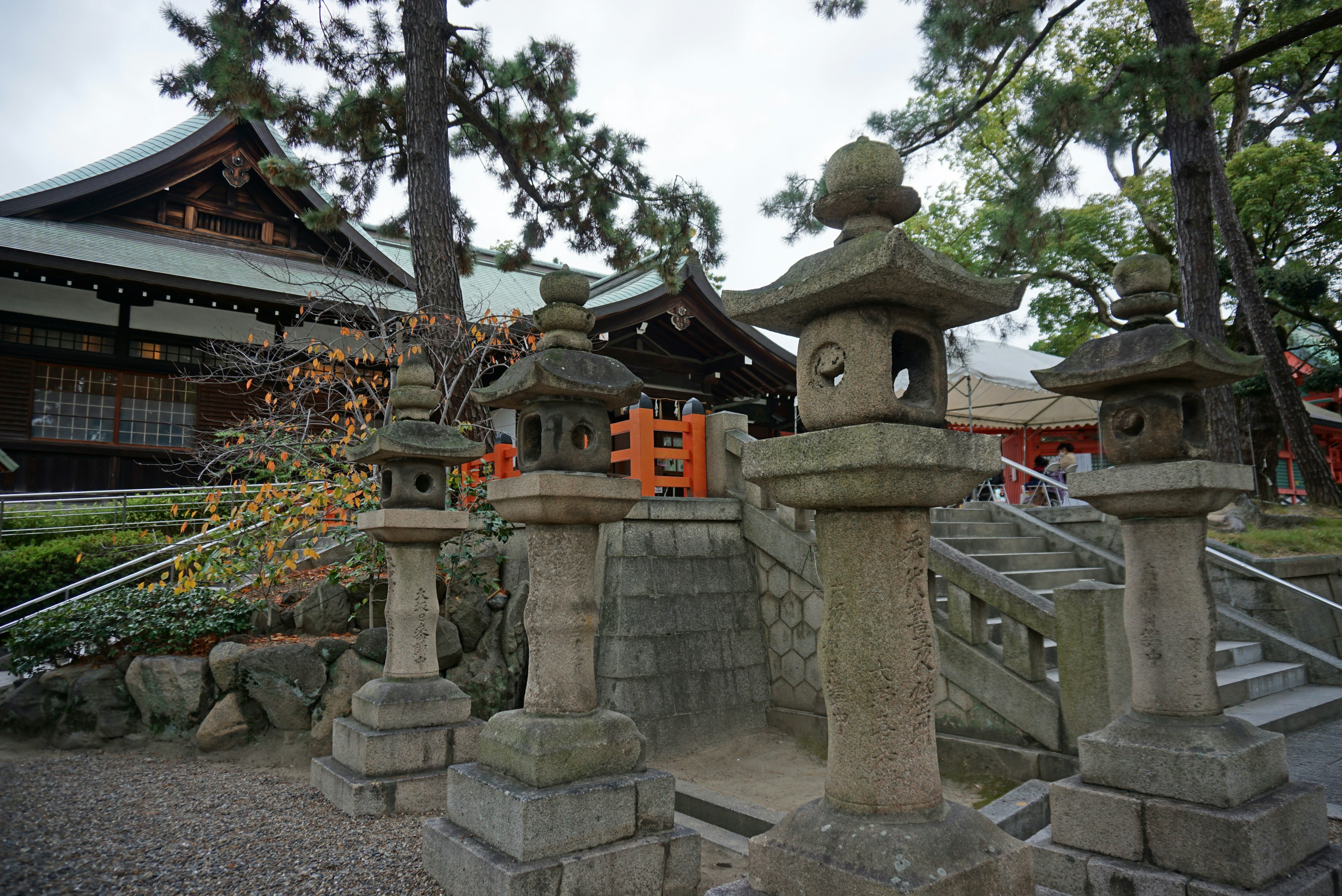 Stone lanterns in front of a Japanese shrine with traditional architecture