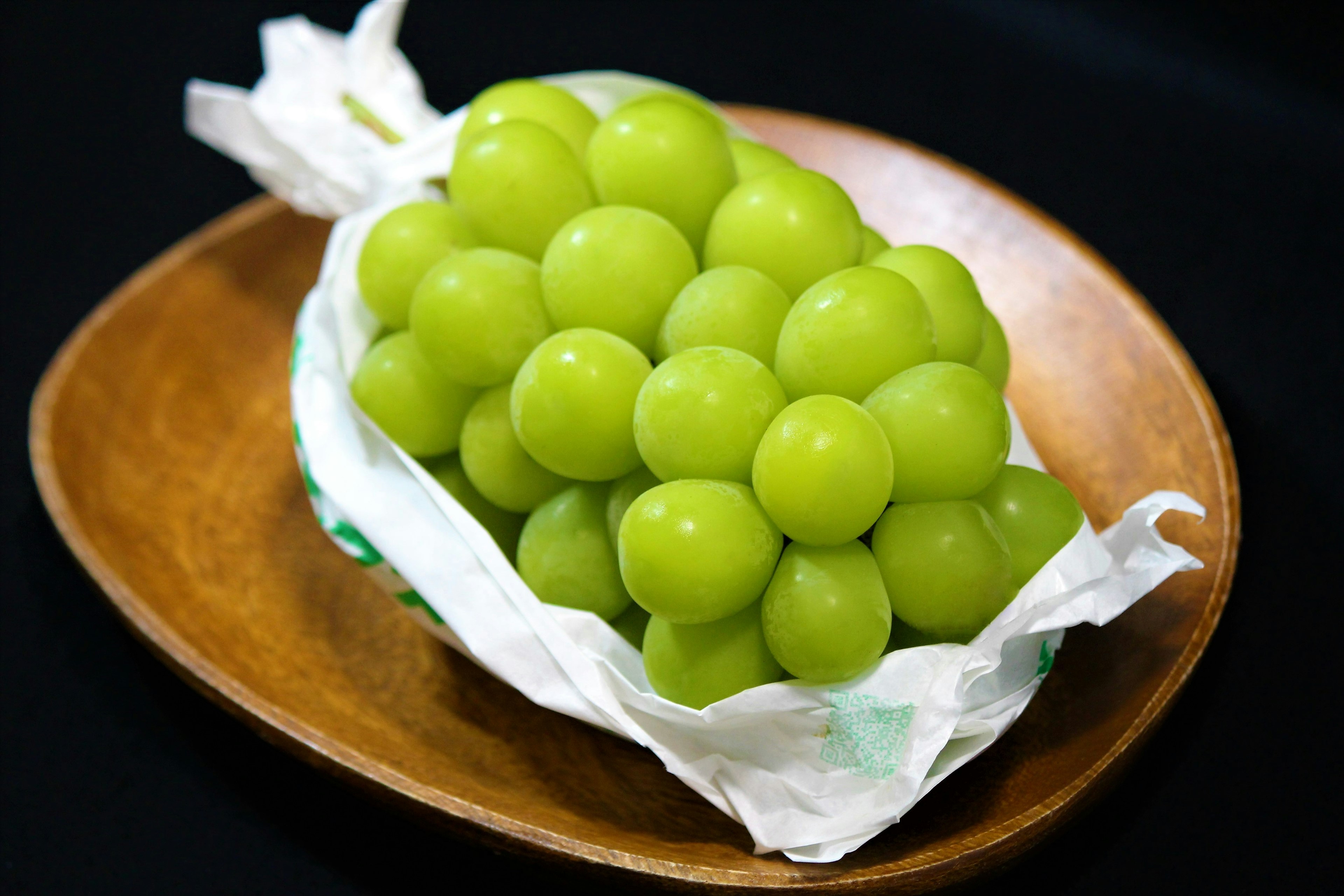 A cluster of green grapes on a wooden plate