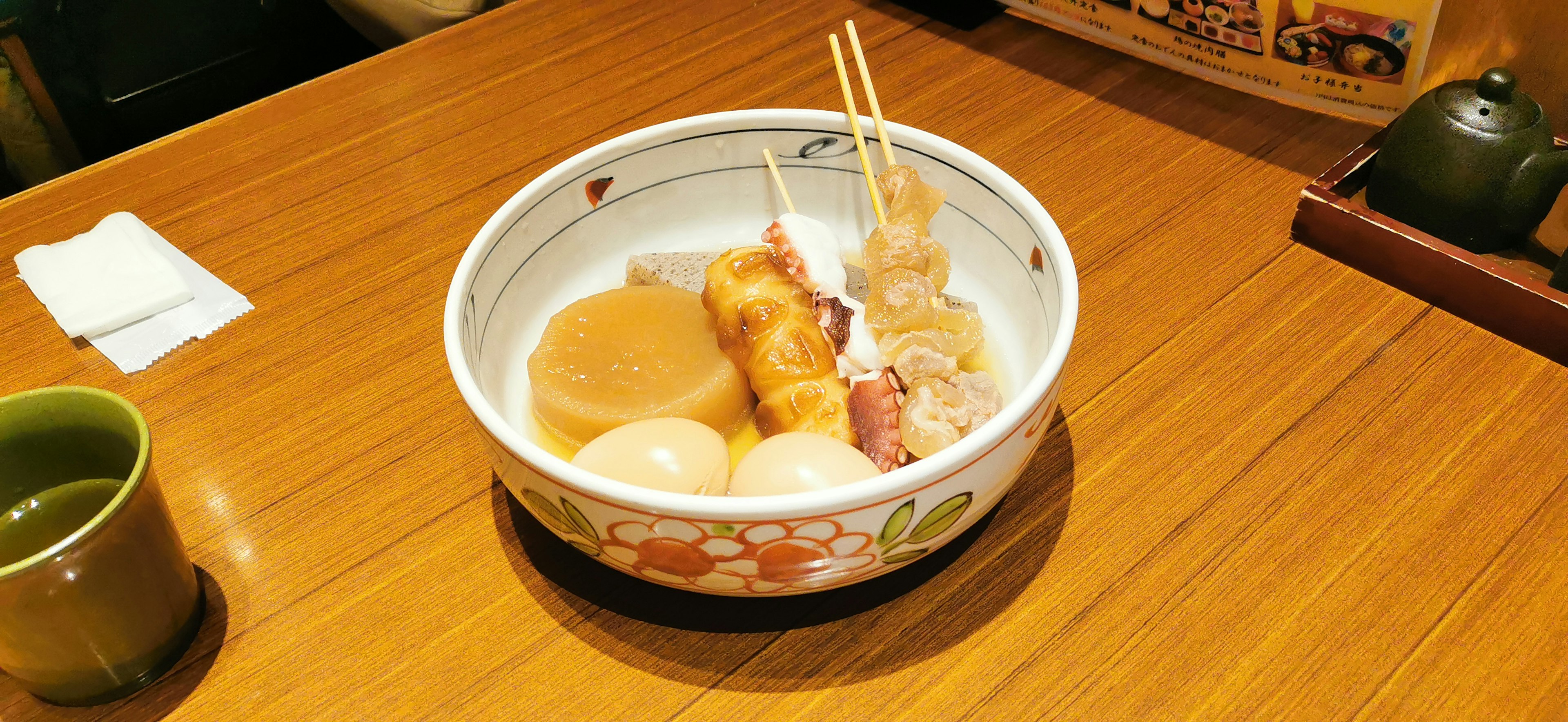 A warm serving of oden in a ceramic bowl placed on a wooden table