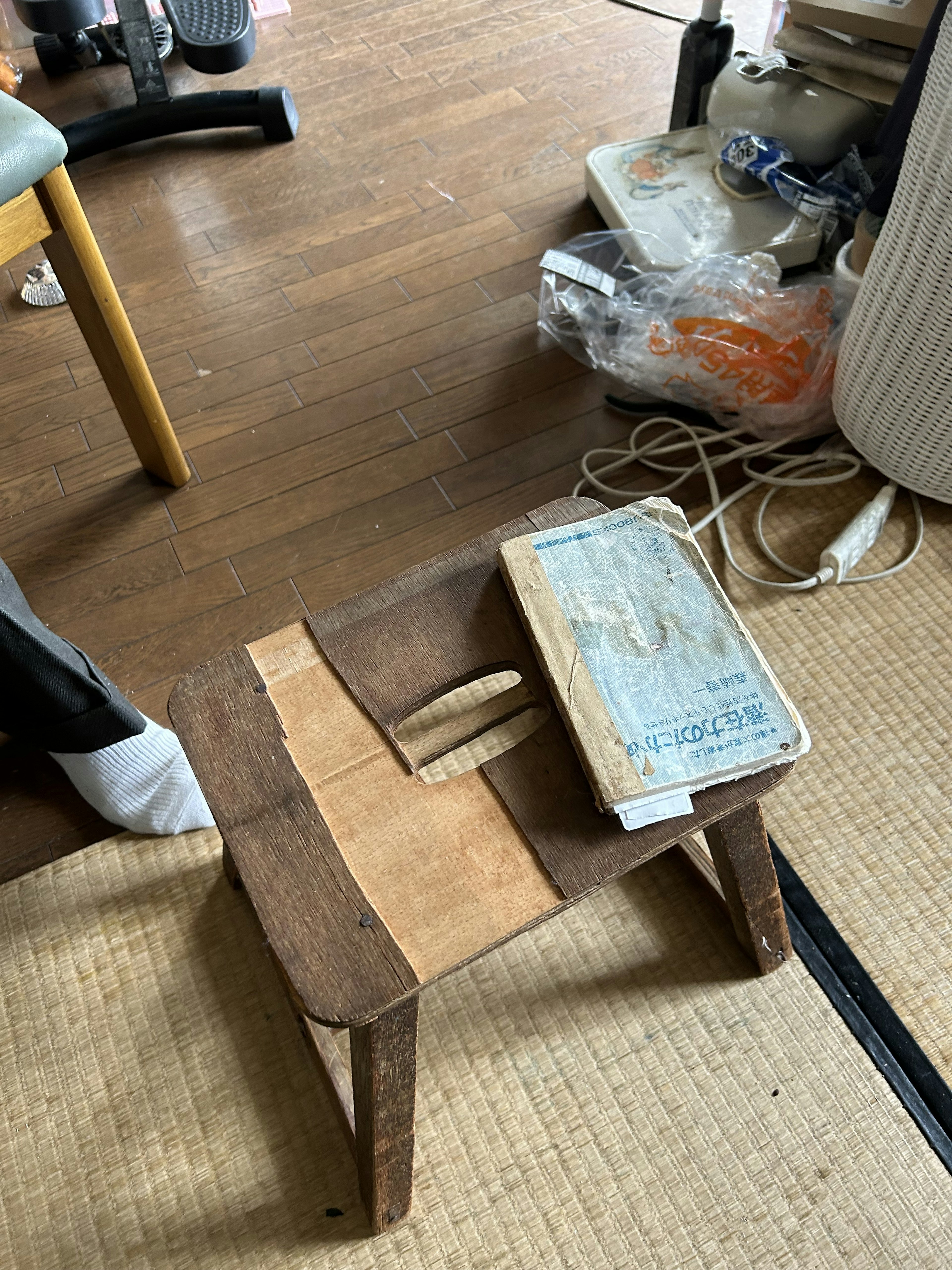 Un petit tabouret en bois avec un livre posé dessus dans un environnement intérieur