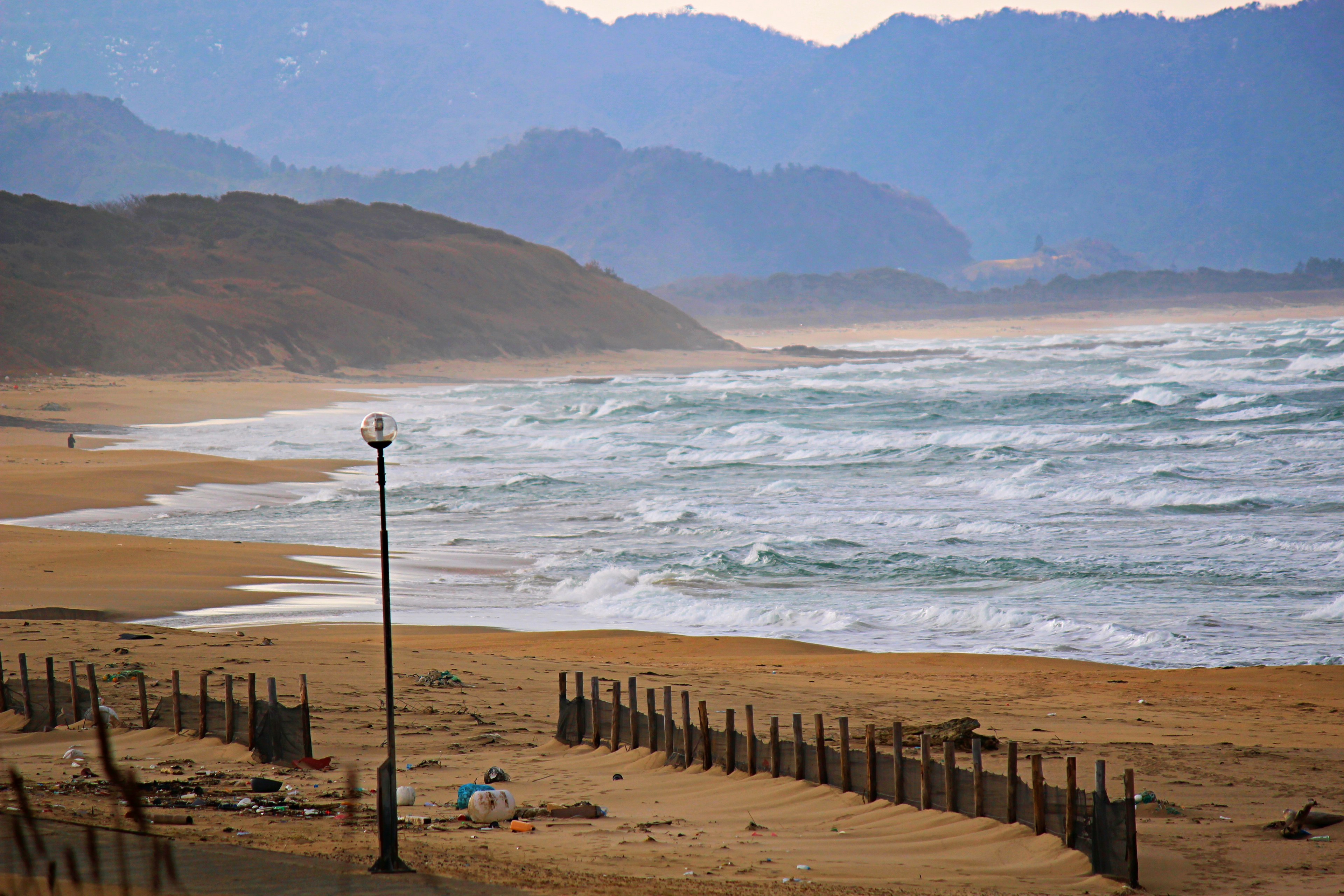 ทิวทัศน์ชายหาดที่เงียบสงบพร้อมคลื่นและภูเขาห่างไกล