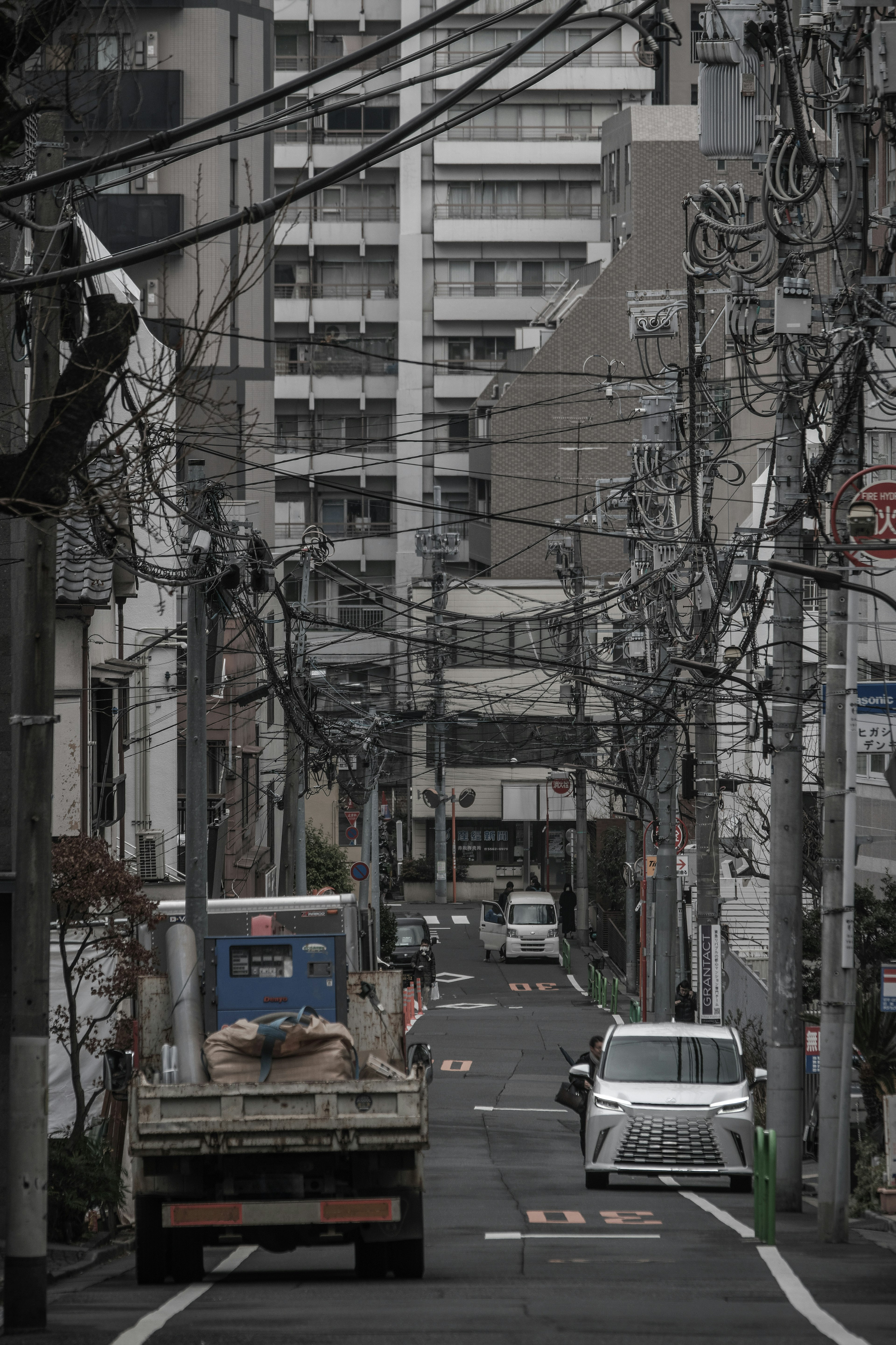 狭い路地に並ぶビルと電柱が特徴的な都市風景